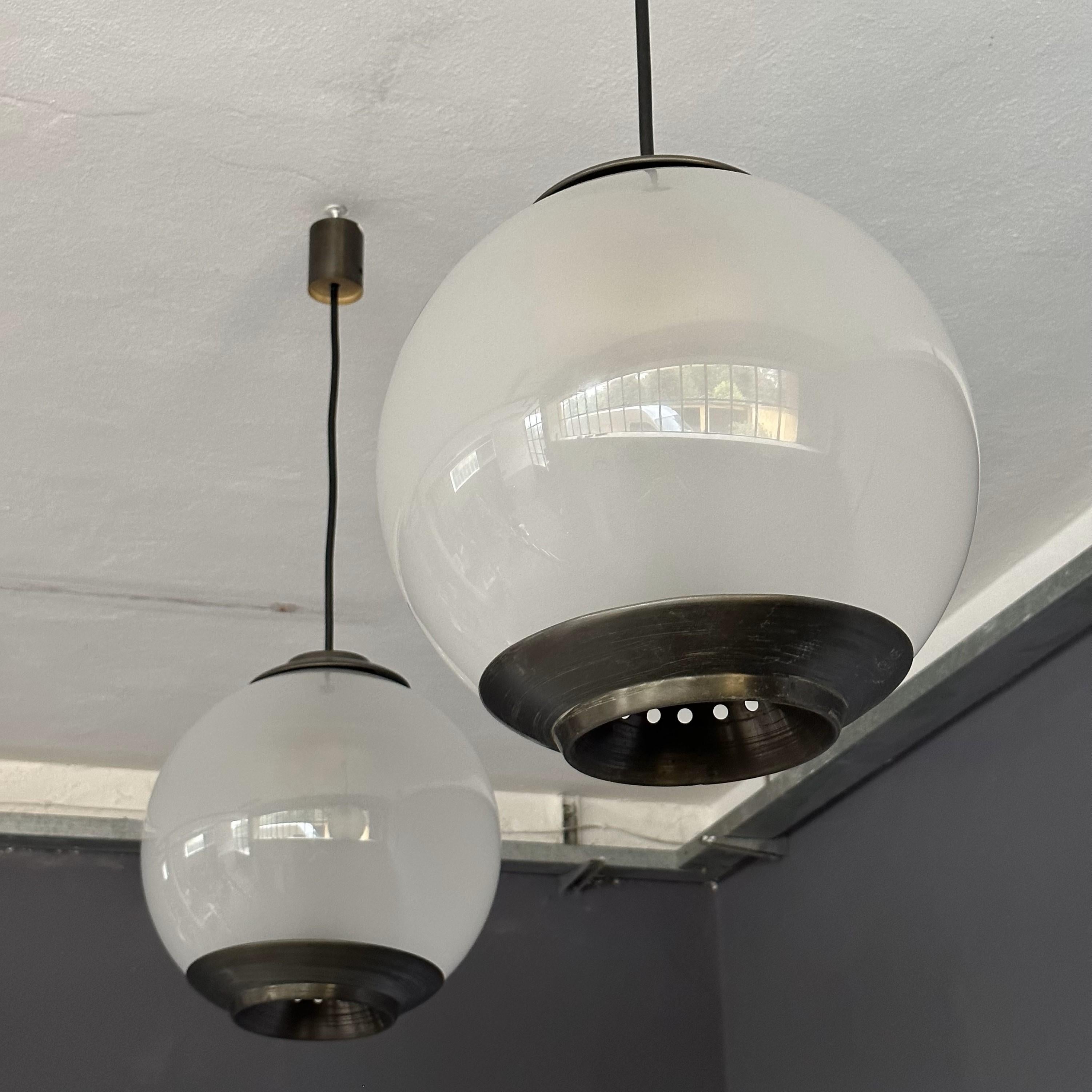 Set of two 'PALLONE' suspension chandeliers, designed by Luigi Caccia Dominioni  for Azucena, 1950s, Italian manufacture.
Brass plates, blown frosted glass shade and black rope with brass ceiling cup.

Diameter: 35cm
Height: 50cm