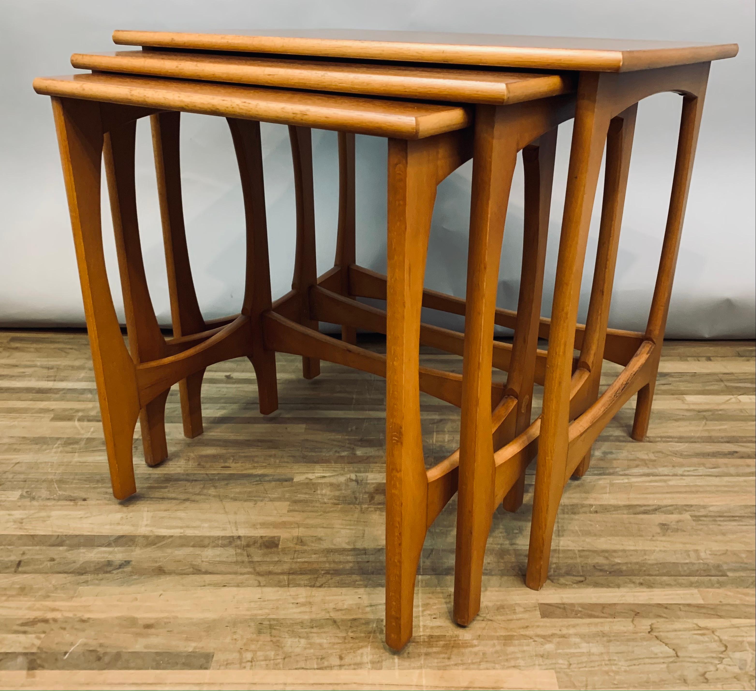 Set of 3, 1960s, nest of teak stackable tables. Made in England. Well-made, sturdy and fully functional. The tables have a wonderful deep and even grain. The tables are designed to slot into one other when not in use and for storage purposes. The