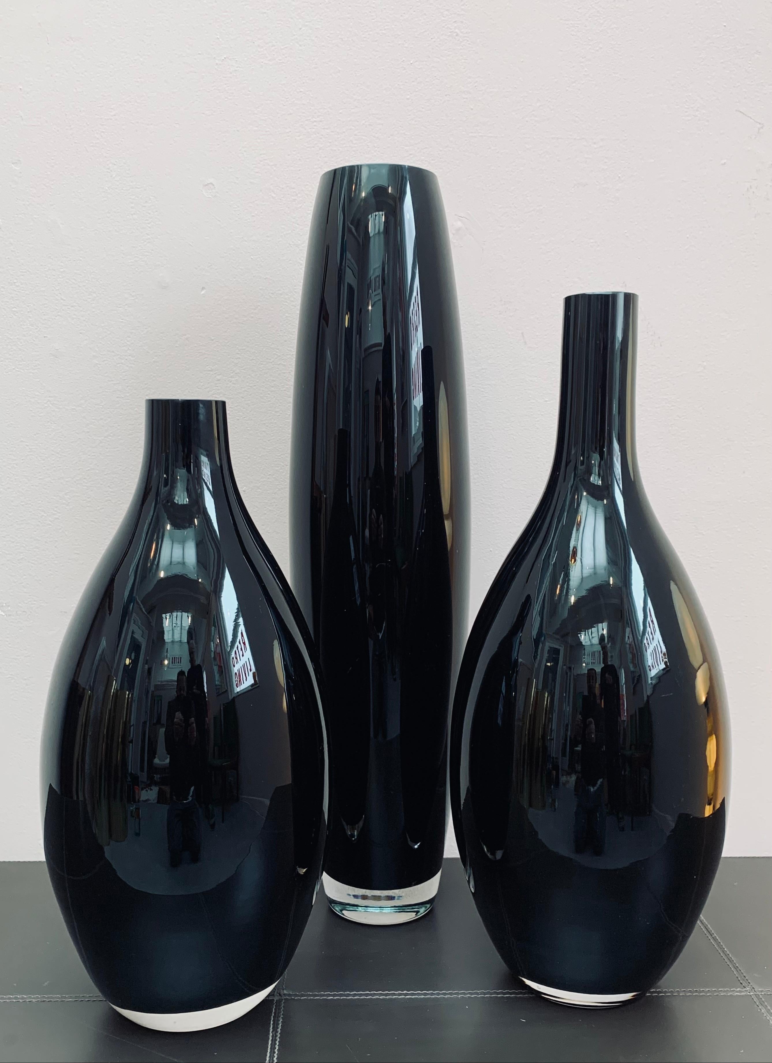 1980s set of three heavy black and clear glass vases of different sizes and proportions which look striking together. Made in England. Some small surface scratches but not particularly noticeable. No chips or cracks. Their bodies are made from black