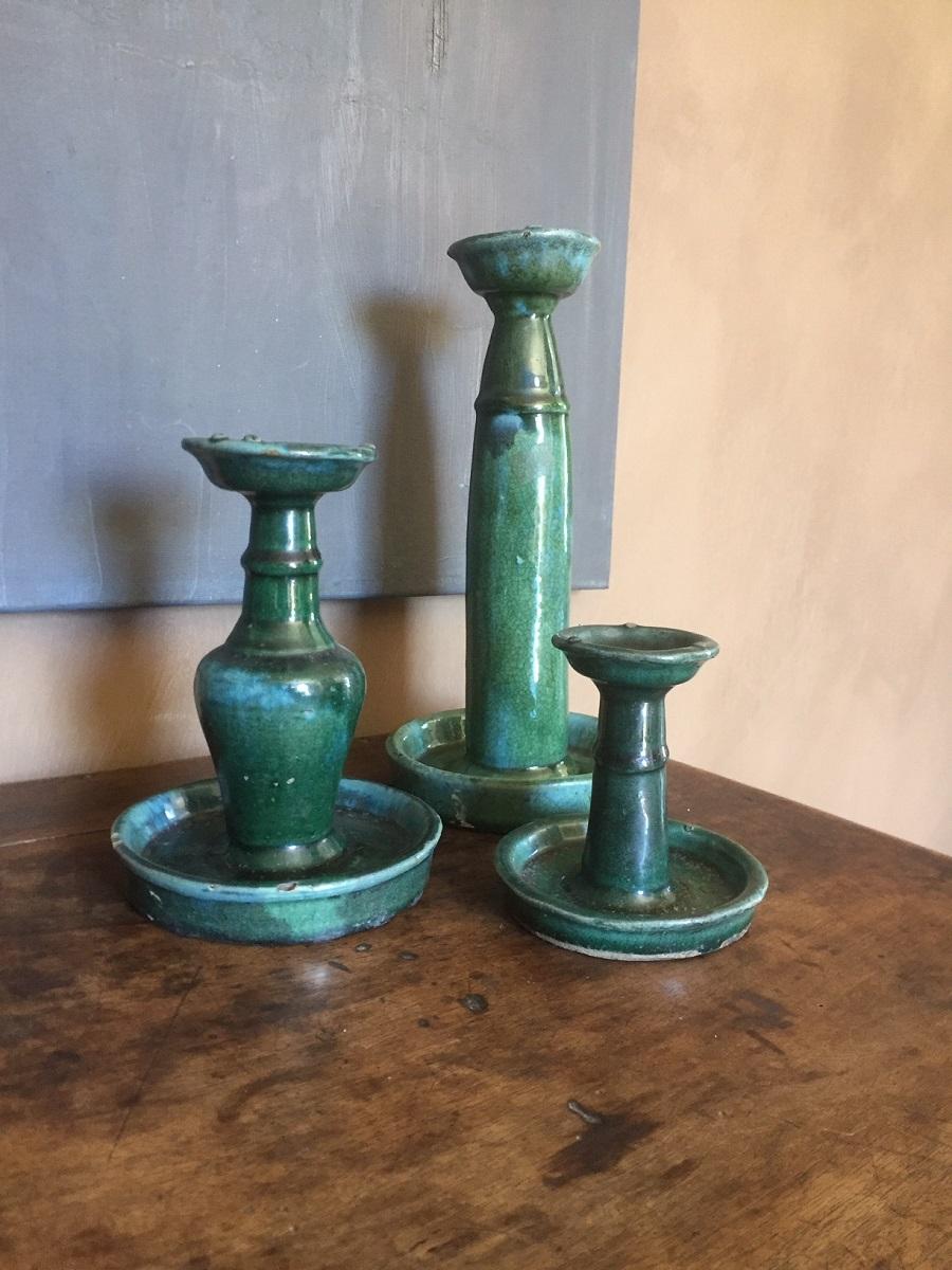 A set of 3 green glazed ceramic candlesticks. All three similar but in a different size (28 cm high, 11 and 19 or in inches 11, 4.3 and 7.5). The glaze wonderfully aged and of a elegant form. These date from around the early 20th century (Qing