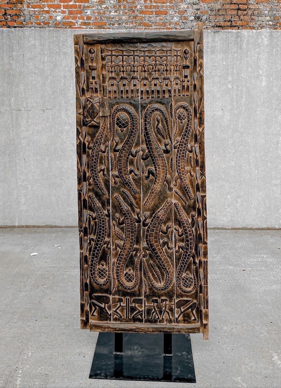 Fantastic set of three carved African doors with custom made black metal sculpture stand. Each door rests on a metal stand with two pegs in the front and a set of holes in the back for screws. 

Door can be sold without metal stand and hung on a