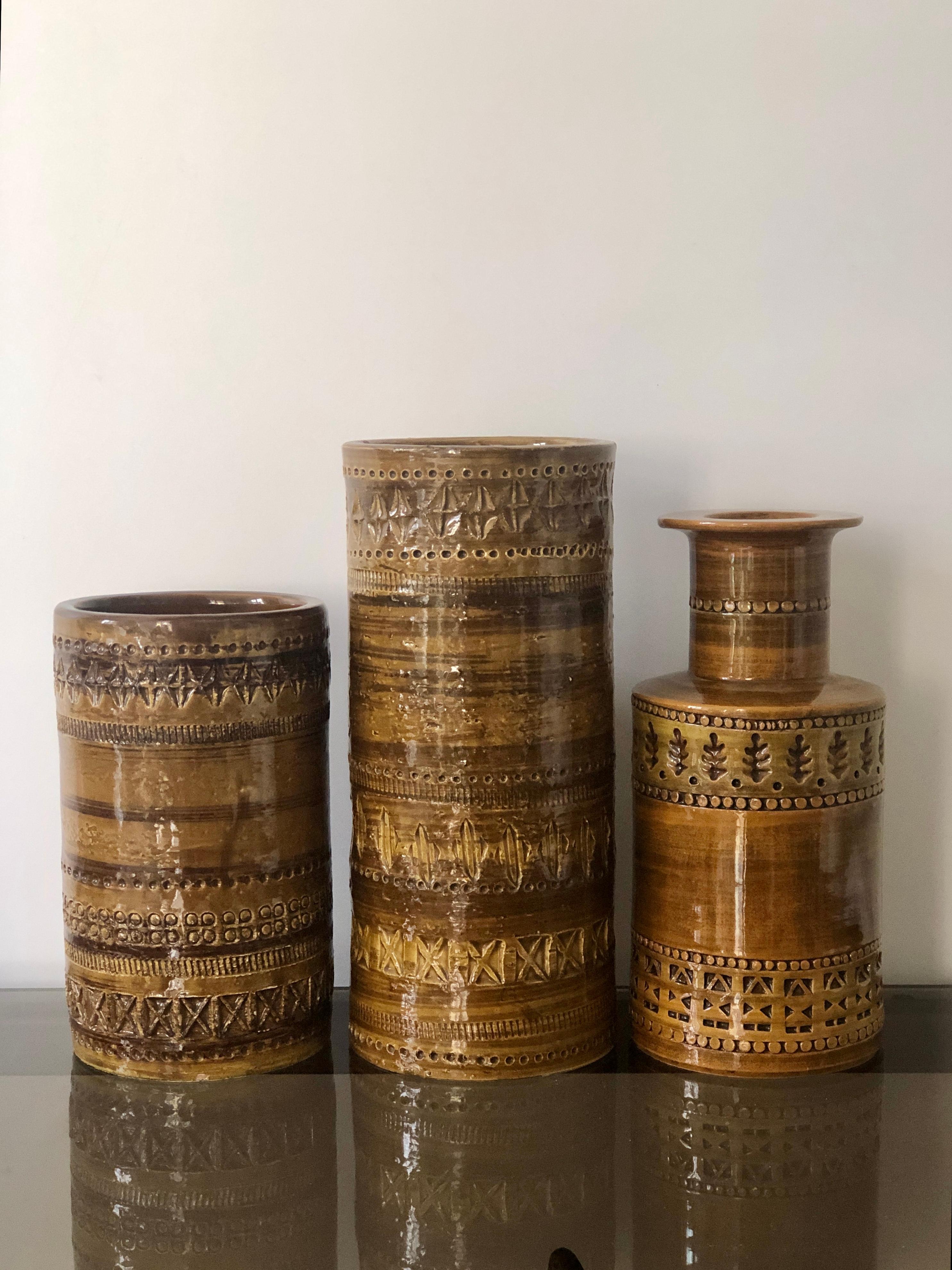 Set of 3 ceramic vases designed by Aldo Londi and manufactured by Bitossi, Italy in the 1960s. Mustard colored with strokes of brown and engraved geometric patterns. Good vintage condition with minor wear to glaze as seen in image. 
The golden