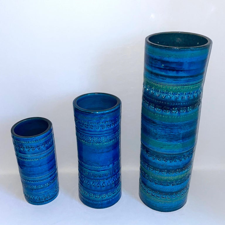 A set of handmade Rimini blue cylindric ceramic vases designed by Aldo Londi and manufactured by Bitossi, Italy in the 1960s. Blue and with some strokes of green glazed ceramic with engraved patterns. Its gorgeous shades of blue and the geometric
