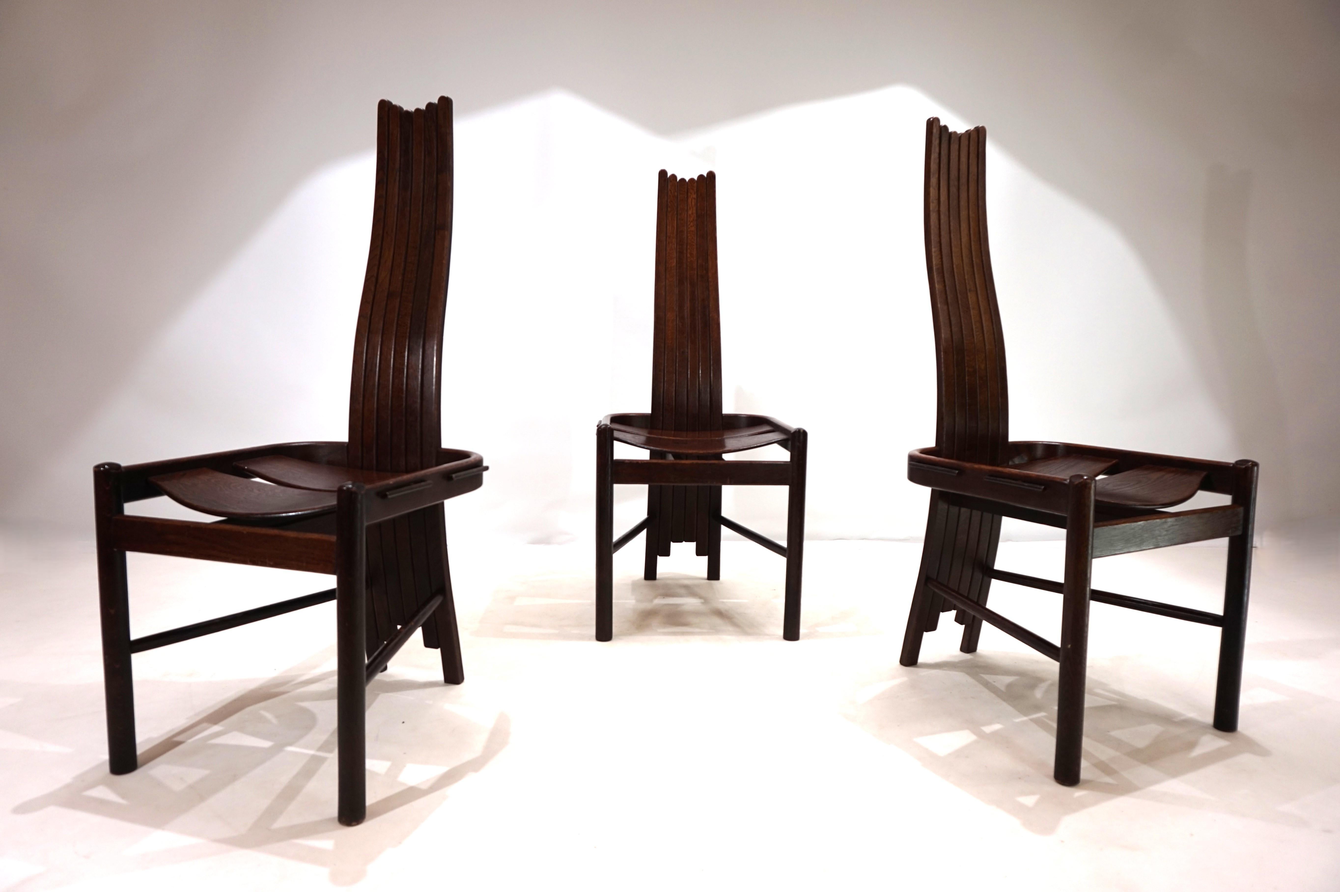 Un set di tre sedie da sala da pranzo estremamente belle in rovere tinto scuro. Il legno presenta segni di usura solo sui piedi e sui montanti esterni del sedile. La forma curva degli schienali, composta da sei montanti, consente una seduta