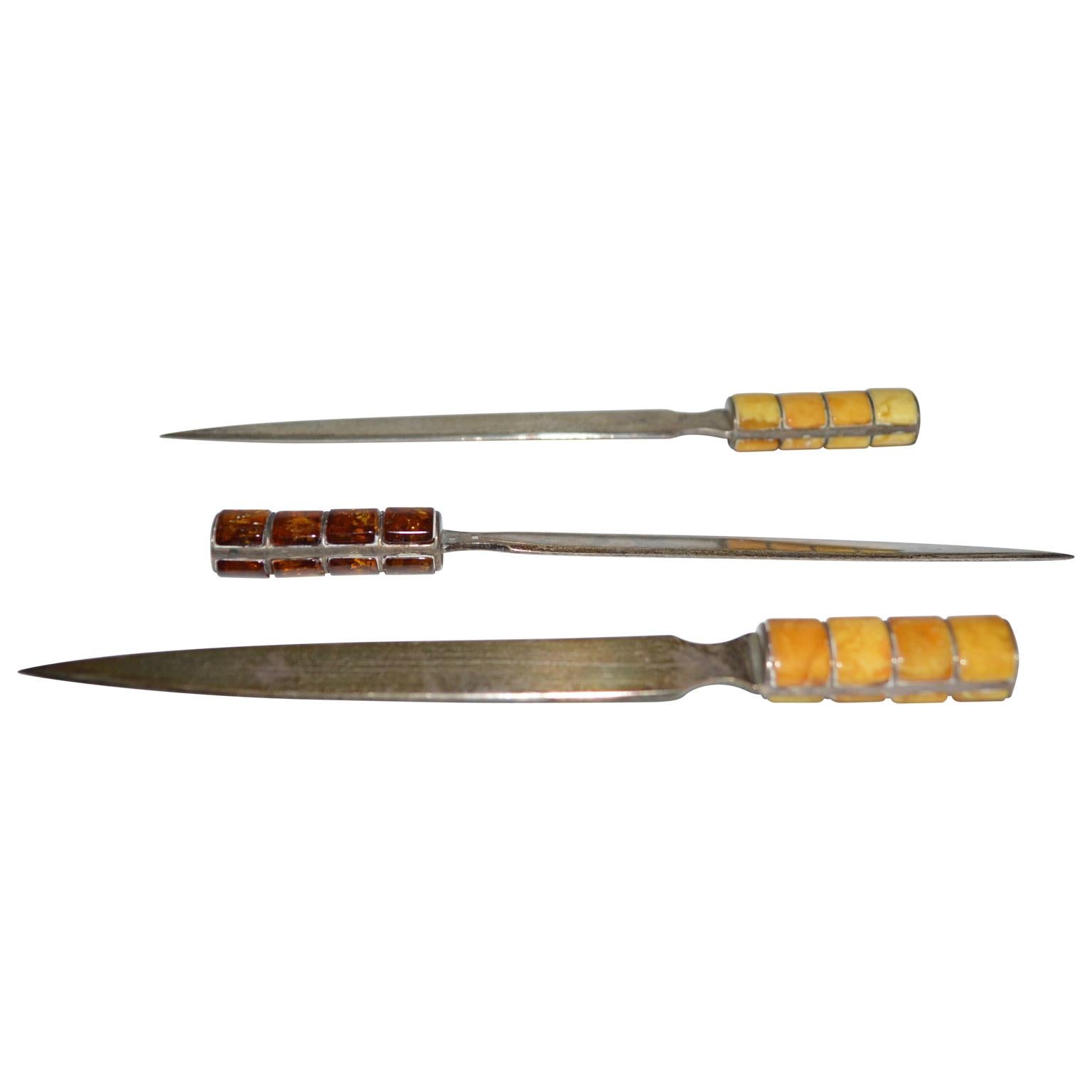 Two letter openers in dark, yellow and nearly white amber. Hallmarked silver.
  
