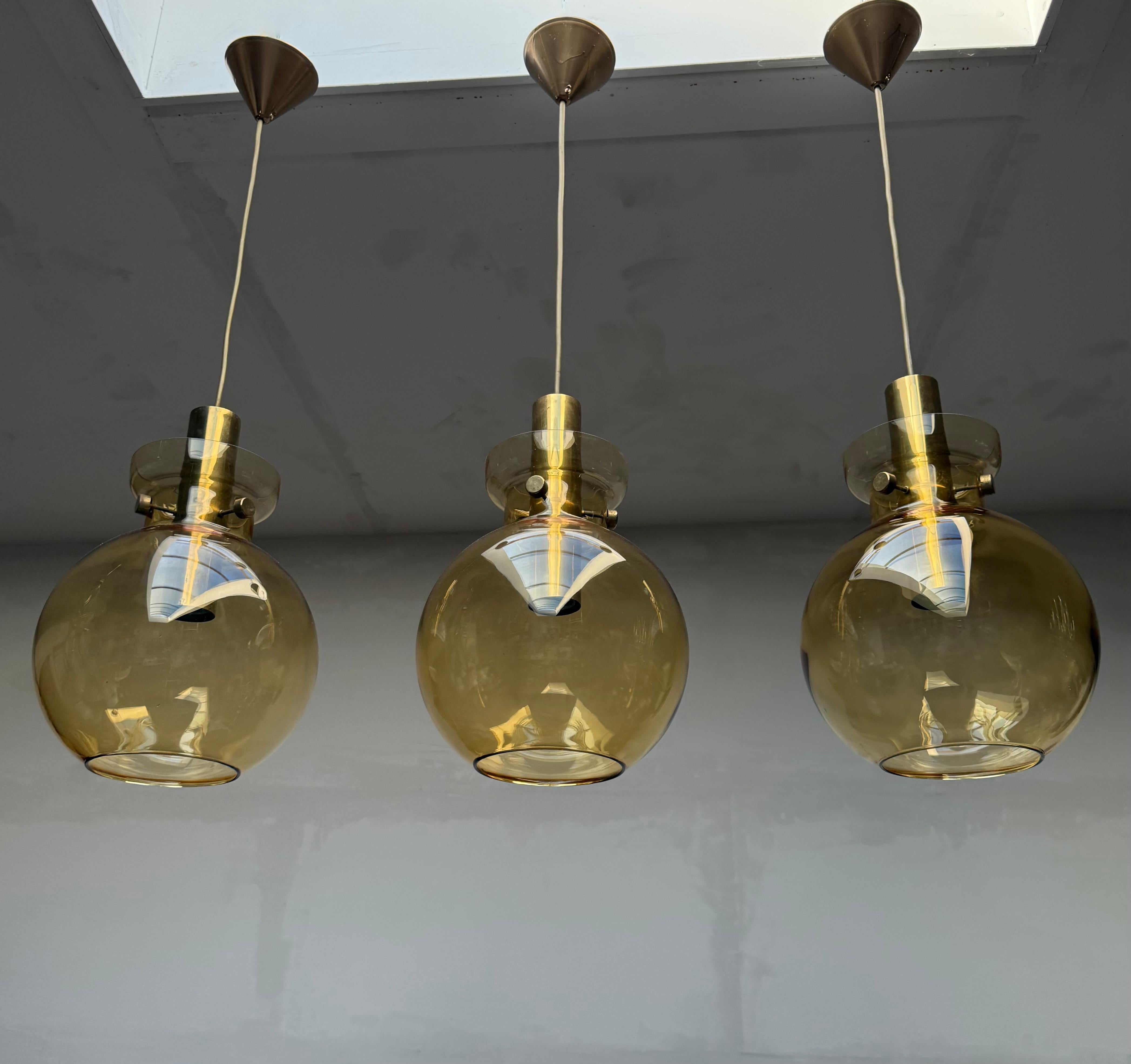 Impresionante juego de tres lámparas colgantes modernas de mediados de siglo, obra de Herbert Proft para Glasshütte, en la década de 1970.

Cada colgante presenta un globo de cristal ámbar soplado a boca con una superficie lisa, elegantemente
