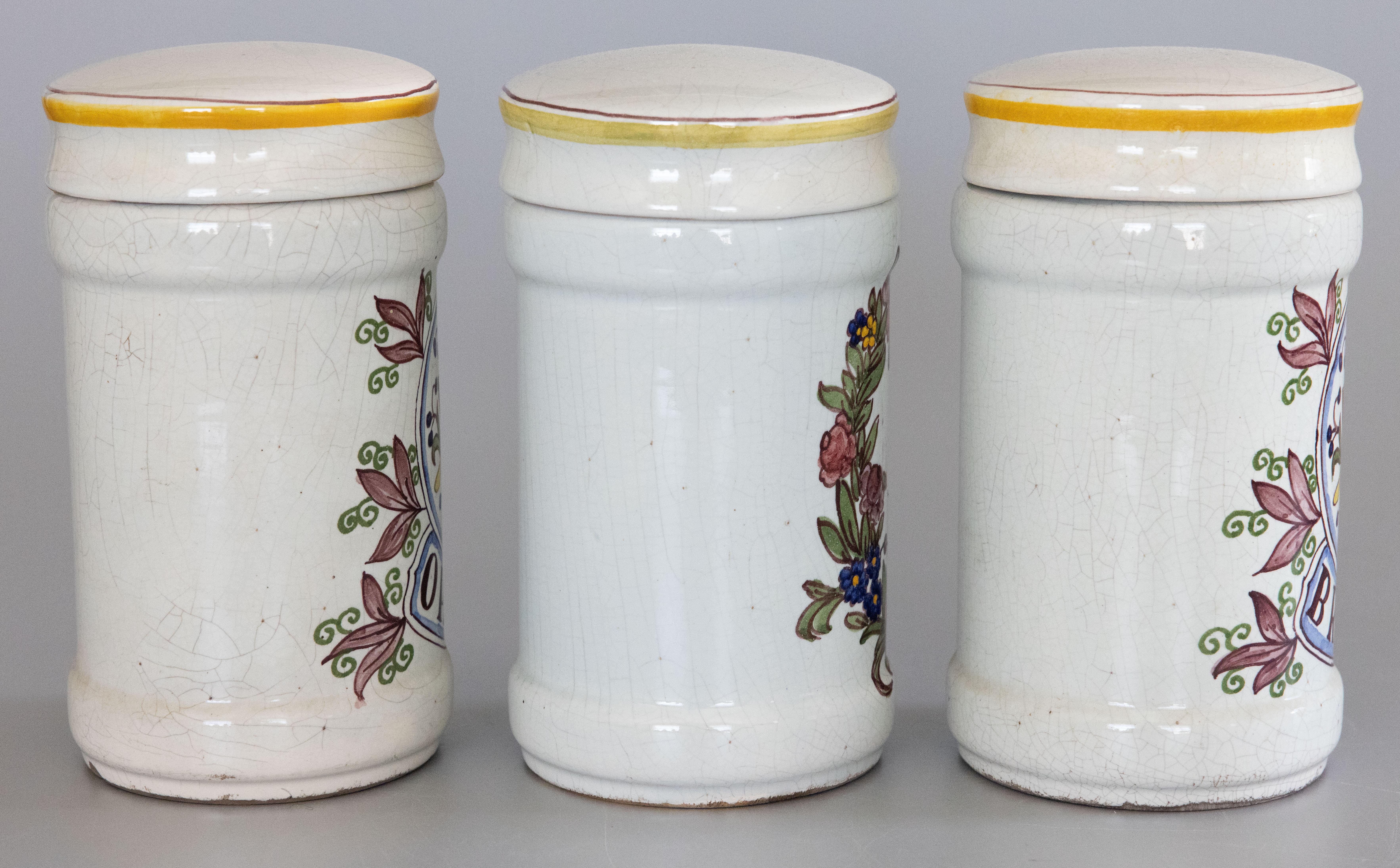 A superb set of three 19th-Century French faience lidded apothecary or pharmacy jars. These fine jars are hand painted with fish, foliage, a garland of flowers and bow, and Latin medicinal names. They would look fabulous displayed on a bathroom