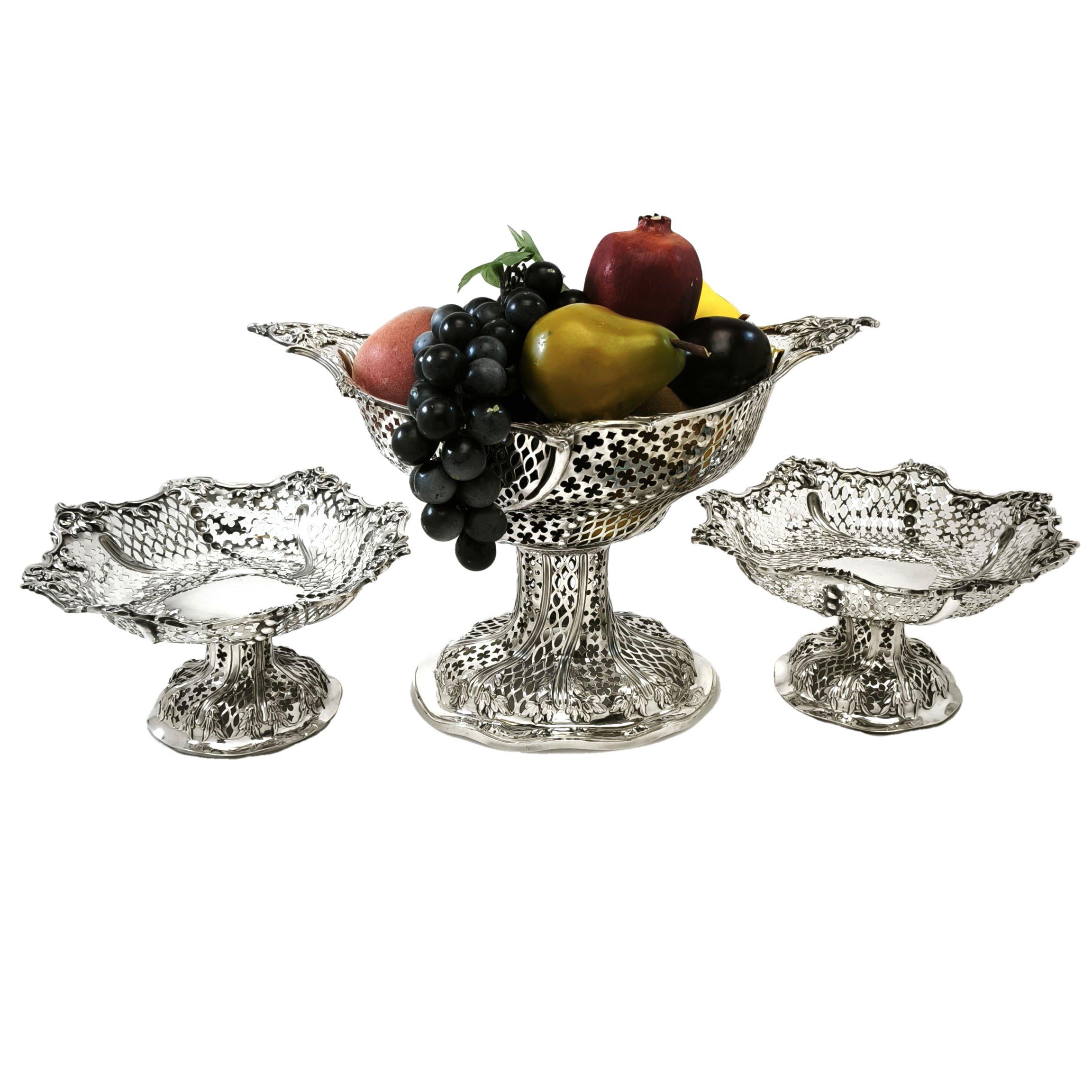 An Antique Victorian Suite of 3 Comports featuring an ornate pierced and chased design across the three pieces. The Set of Victorian Baskets features a tall centre Comport in a lens shape and a pair of lower round Comports, all embellished with the