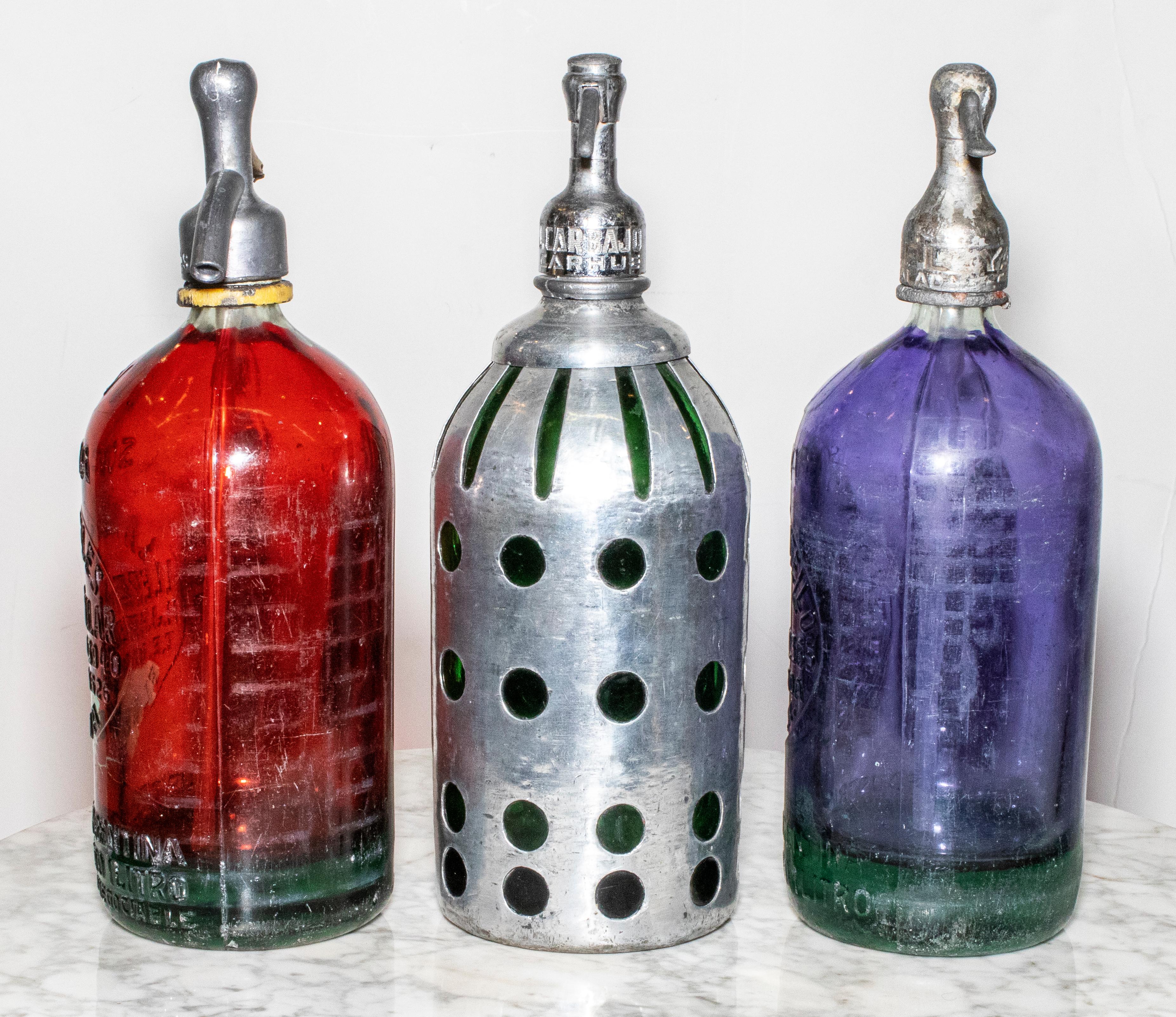 Set of 3 Argentina Art Deco seltzer bottles. Rare colors including red, purple, and green with chrome cover.