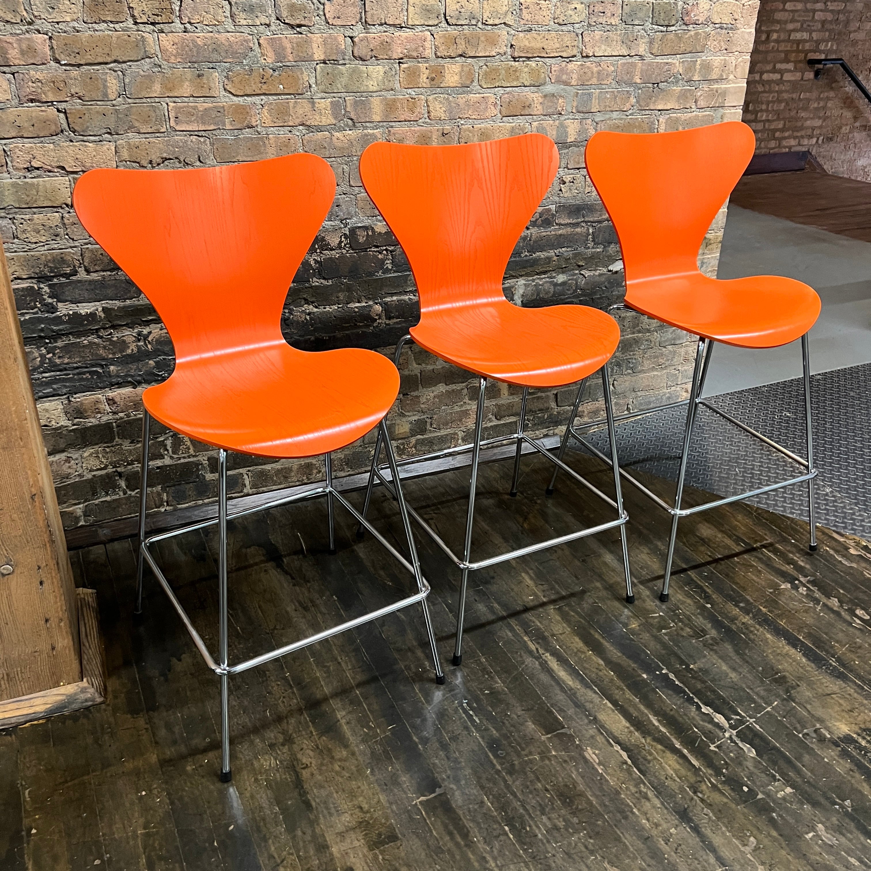 This is a beautiful set of 3 Arne Jacobsen Series 7 counter height stools (#3187) have four-sided footrests in tubular steel fixed to the extended legs. They were launched in 2005 to honor the 50th anniversary of the Series 7 design.  This