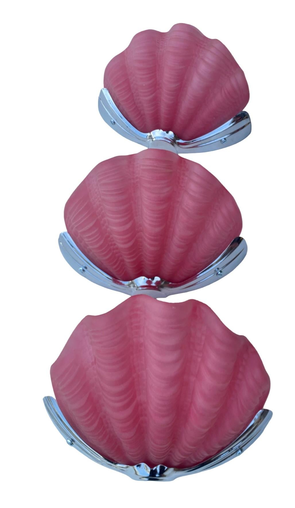 Precioso conjunto de 3 apliques de concha Art Decó. Los tonos están en excelente estado y son de un precioso rosa caramelo. Se sujetan firmemente mediante pequeños soportes cromados y se asientan perfectamente en la placa posterior cromada, también