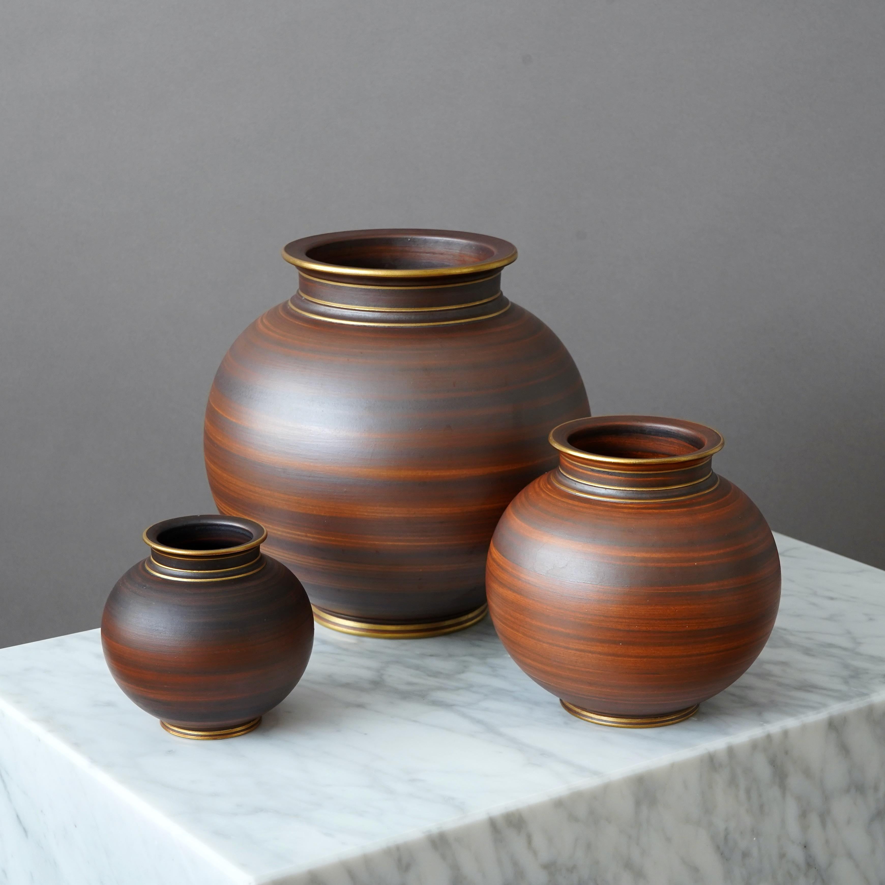 Set of 3 stoneware art deco vases with beautiful brown glaze. Foot and mouth detailed in gold.
Designed by Gunnar Nylund for ALP (Lidköpings Porslinsfabrik), Sweden, 1930s.

Excellent condition.
Stamped 'ALP', 'Modell Nylund', 'Lidköping, SWEDEN'