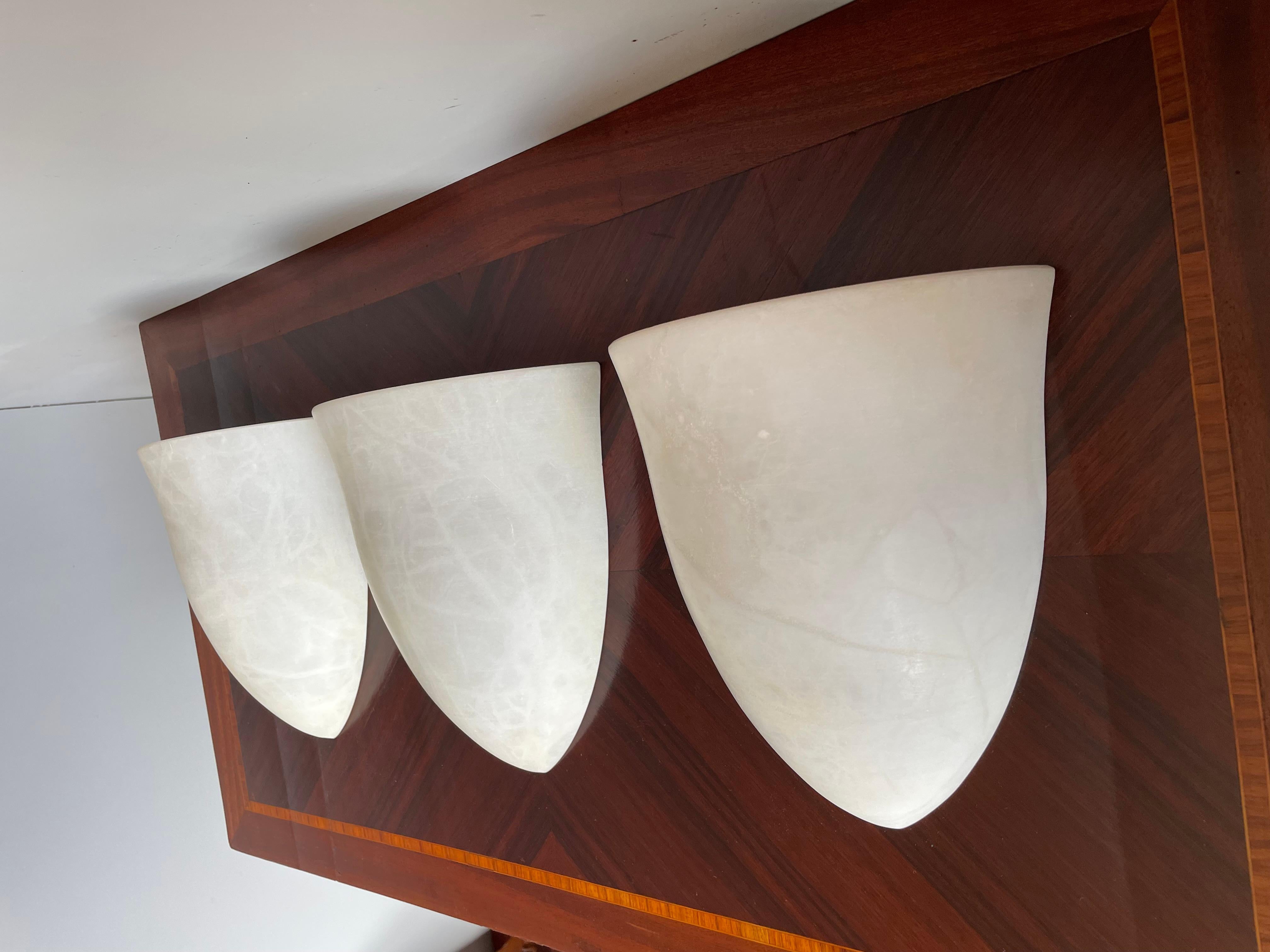 Handcrafted and very stylish set of midcentury made alabaster wall lights.

If you are looking for a great design and practical size trio of sconces to grace your living space then these natural mineral stone fixtures could be perfect. All