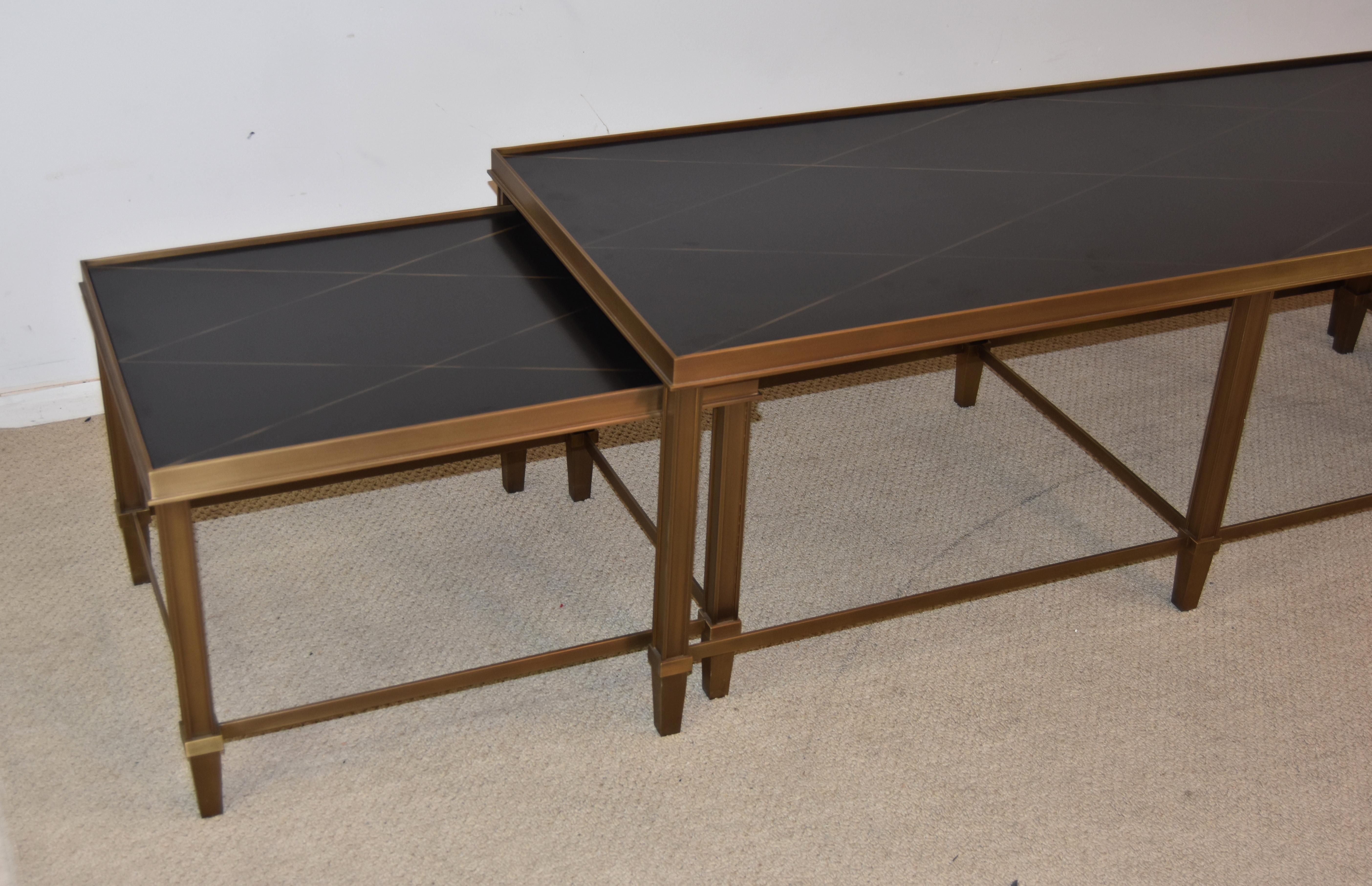 Beautiful 3 piece Baker nesting coffee table set in the Harlequin design by Bill Sofield. These pieces are in great condition. They have bronze frames and black lacquered wood tops. The tops display a gold detail work in a Harlequin design. The 2