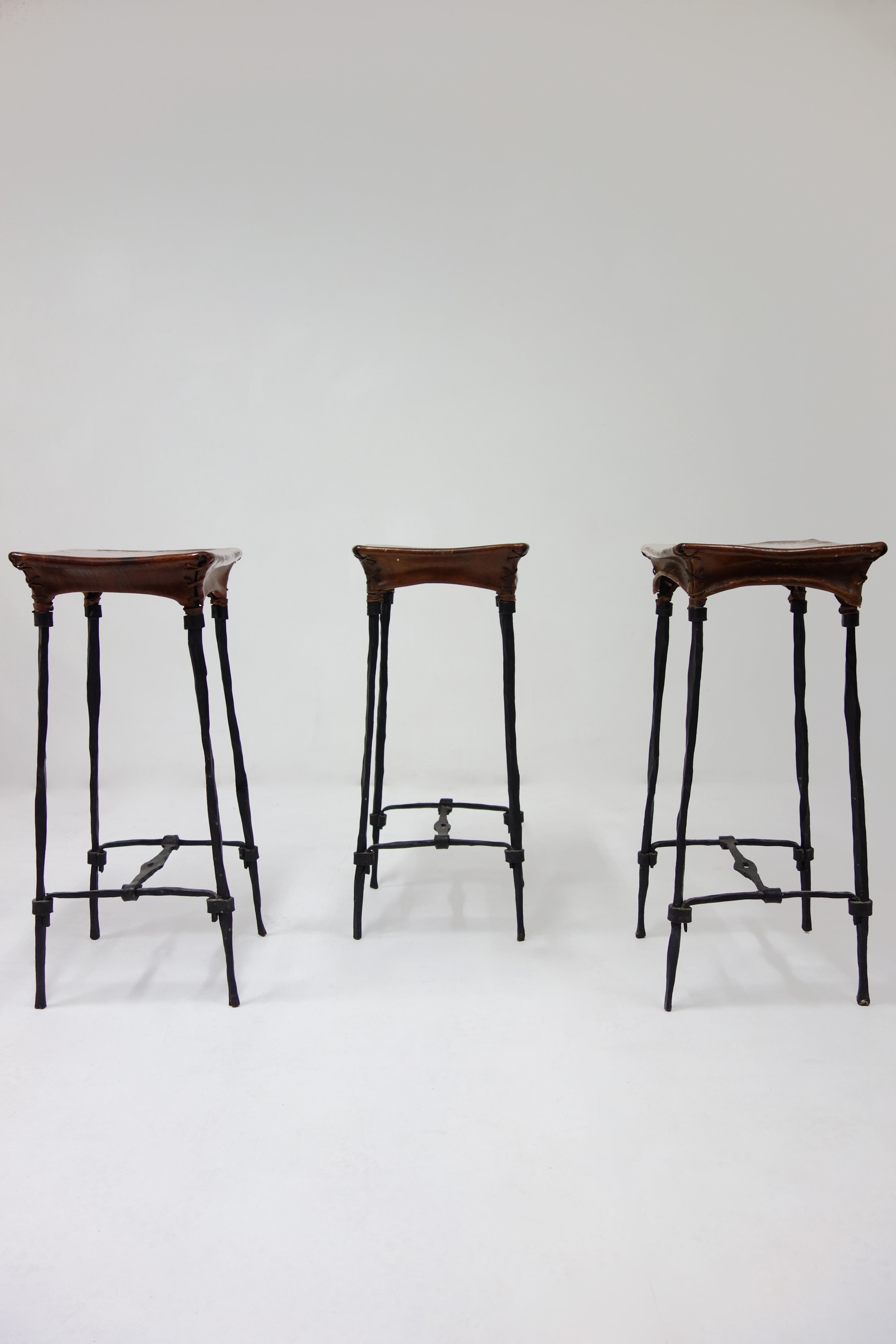 Set of 3 bar stool by François & Sido Thevenin with a black wrought iron structure and avbrown patina leather. François and Sido Thevenin give life to metal thanks to their great mastery of forging. This model is rare in this bar stool version. 
 