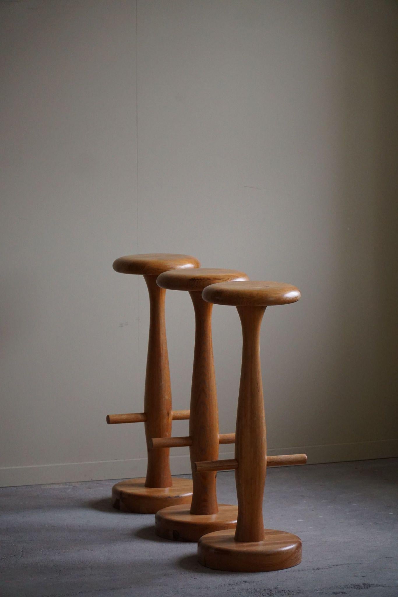 Un encantador conjunto de tres taburetes de bar redondos fabricados en roble macizo, con una elegante silueta en forma de reloj de arena. Estos taburetes se atribuyen al diseñador danés Rainer Daumiller, y encarnan la esencia del diseño moderno