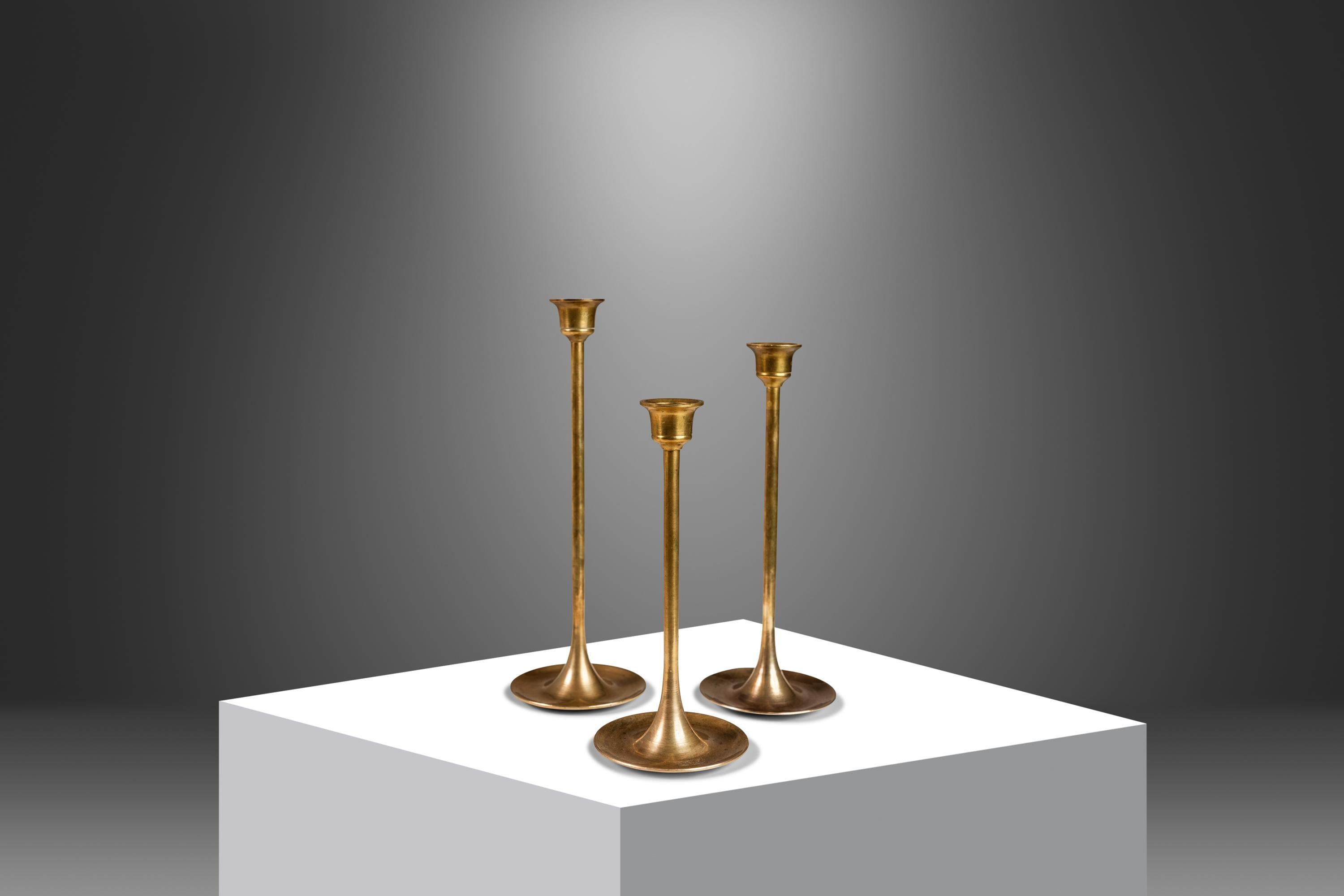  Introducing a splendid set of three solid brass candlestick holders. Constructed in an aesthetically pleasing graduated height and featuring lovely tulip-shaped tops this artfully crafted Bauhaus-styled set is the perfect subtle addition to any