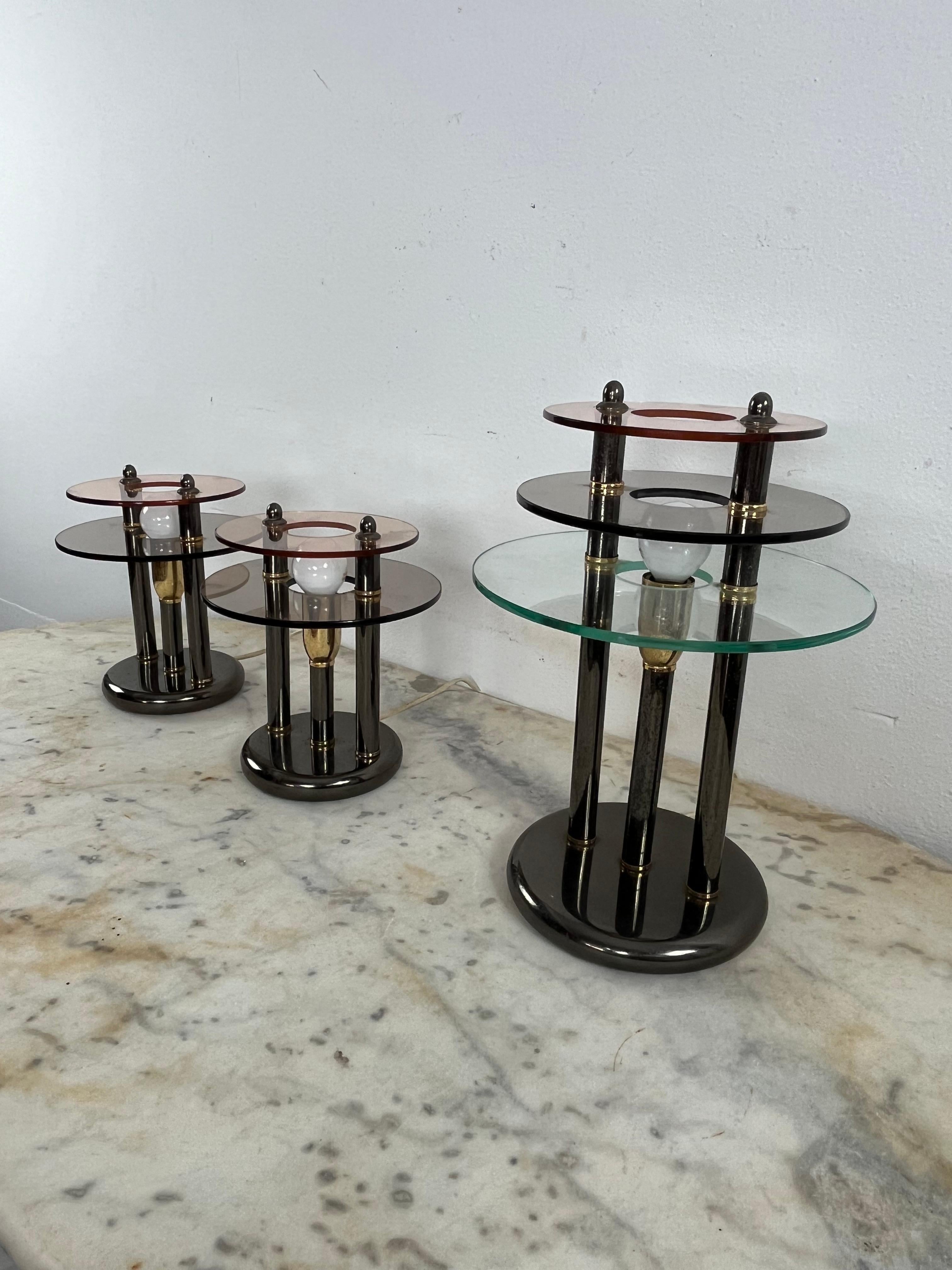 Set of 3 bedroom lamps in metal and colored Murano glass, 1980s
The large one is 33 cm high and has a diameter of 24 cm. The two small ones have a height of 23 cm and a diameter of 20 cm.
E14 lamps. 
Glasses intact. Small signs of aging on the metal
