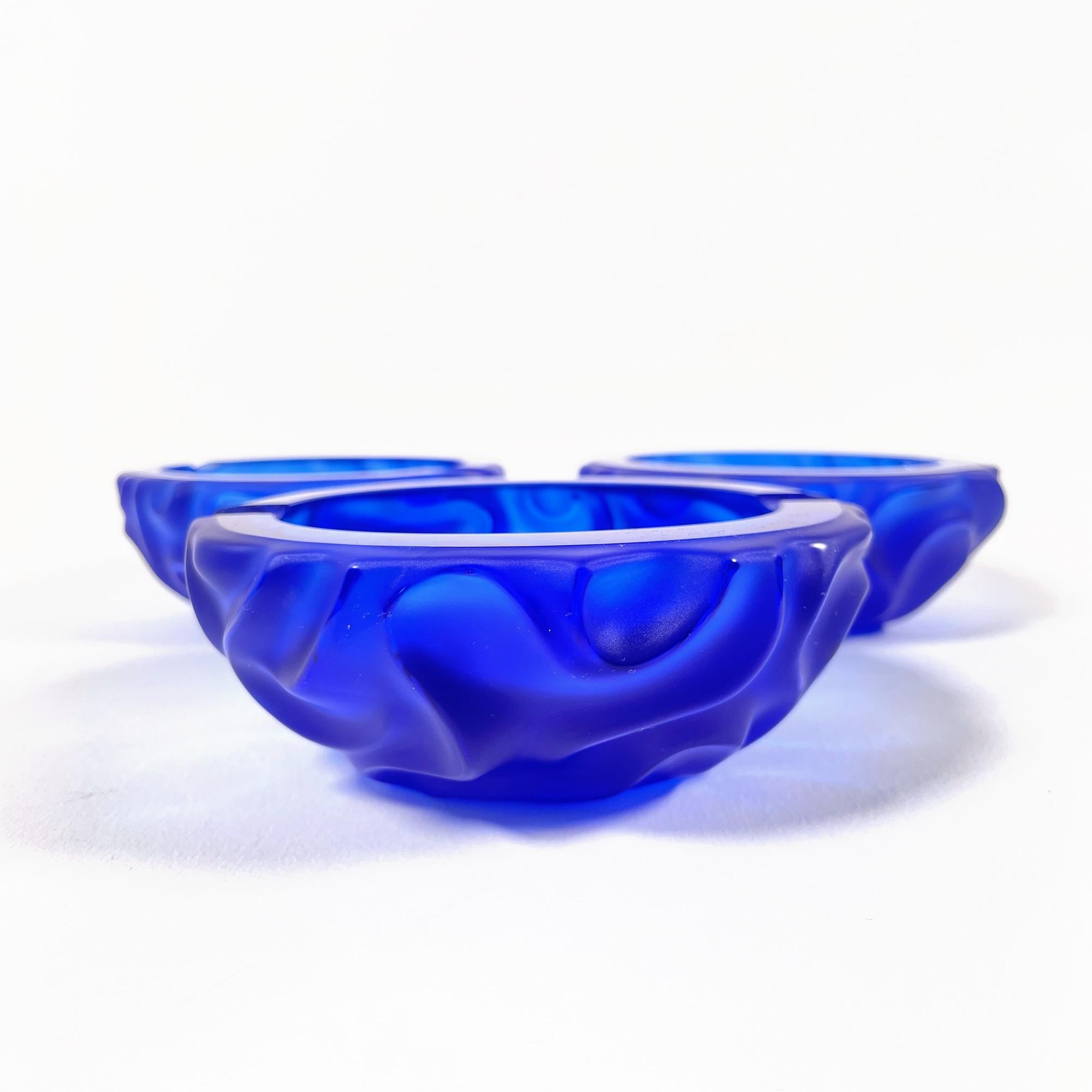 Magnifiques cendriers en cristal dans une teinte bleu profond, rappelant le style distinctif de la célèbre maison Daum. Ces pièces élégantes et intemporelles des années 1970-1980 apporteront une touche de sophistication à votre