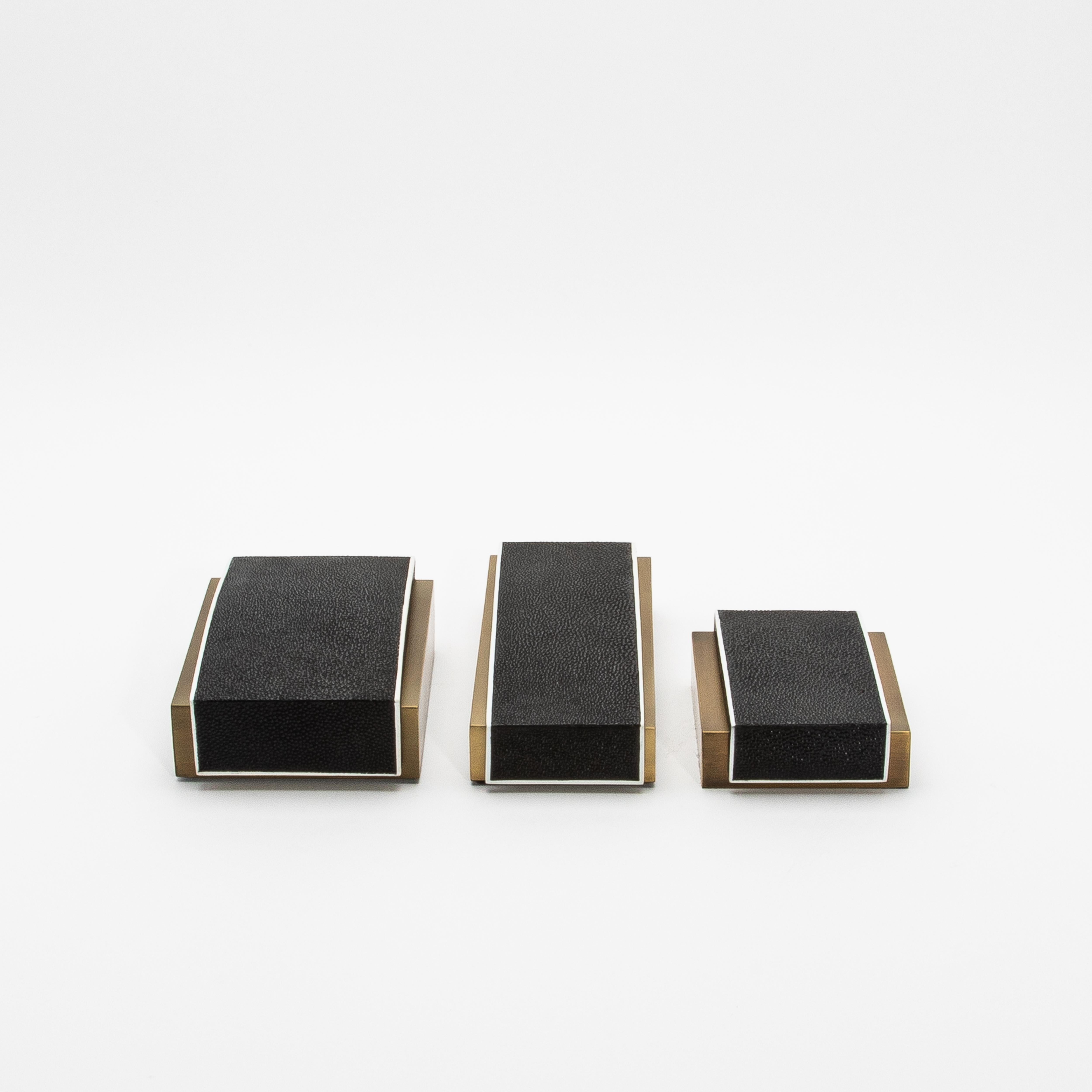 Este elegante conjunto de 3 cajas de escritorio de R&Y Augousti ejemplifica el equilibrio perfecto entre la elegancia moderna y el lujo atemporal. Fabricada en piel de zapa negra con la parte superior curvada, cada caja queda realzada por su base de