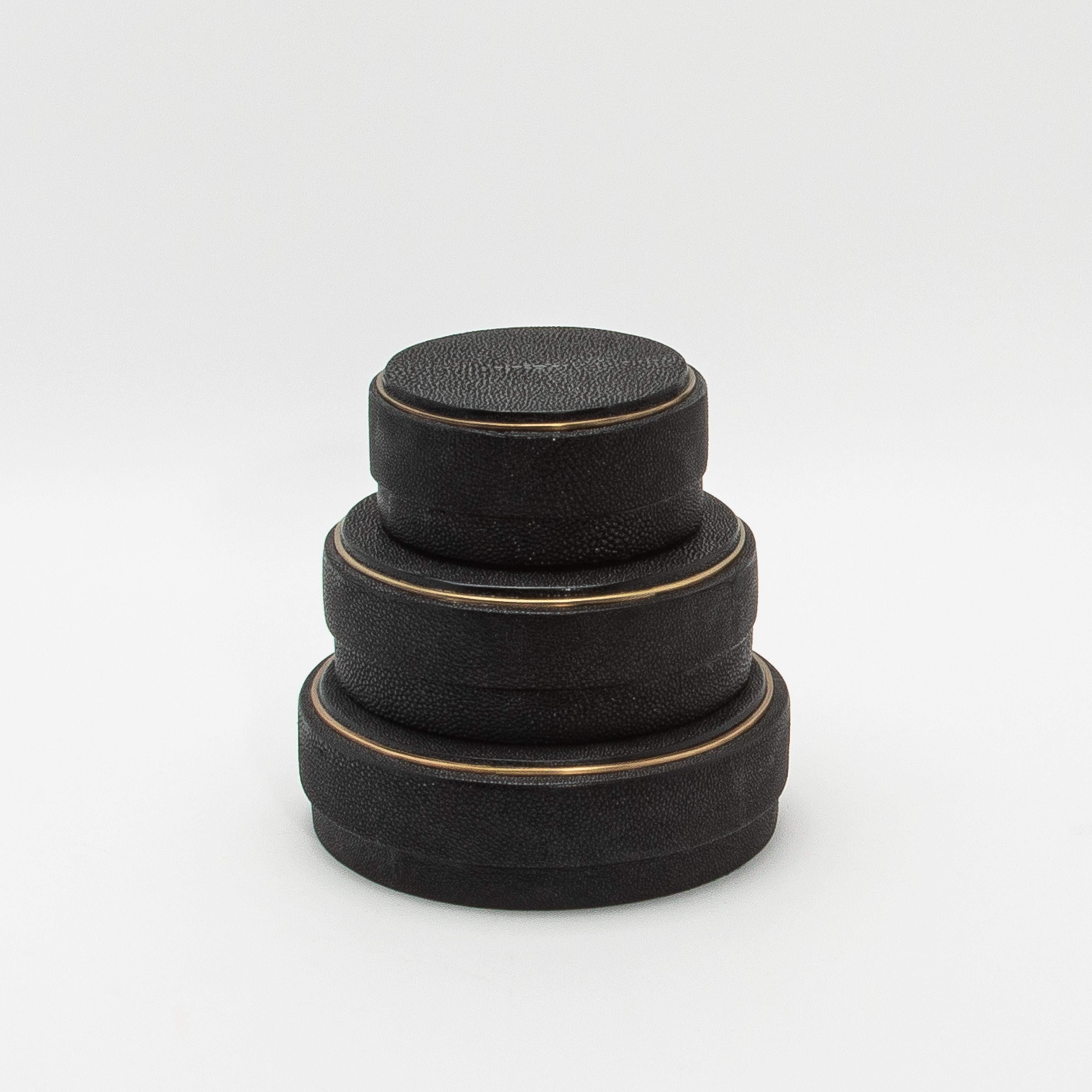 Cet ensemble de 3 boîtes rondes en galuchat noir de R&Y Augousti présente un design qui marie harmonieusement la forme et la fonction. Chaque boîte présente une forme circulaire parfaitement symétrique, dégageant une élégance moderne qui attire le
