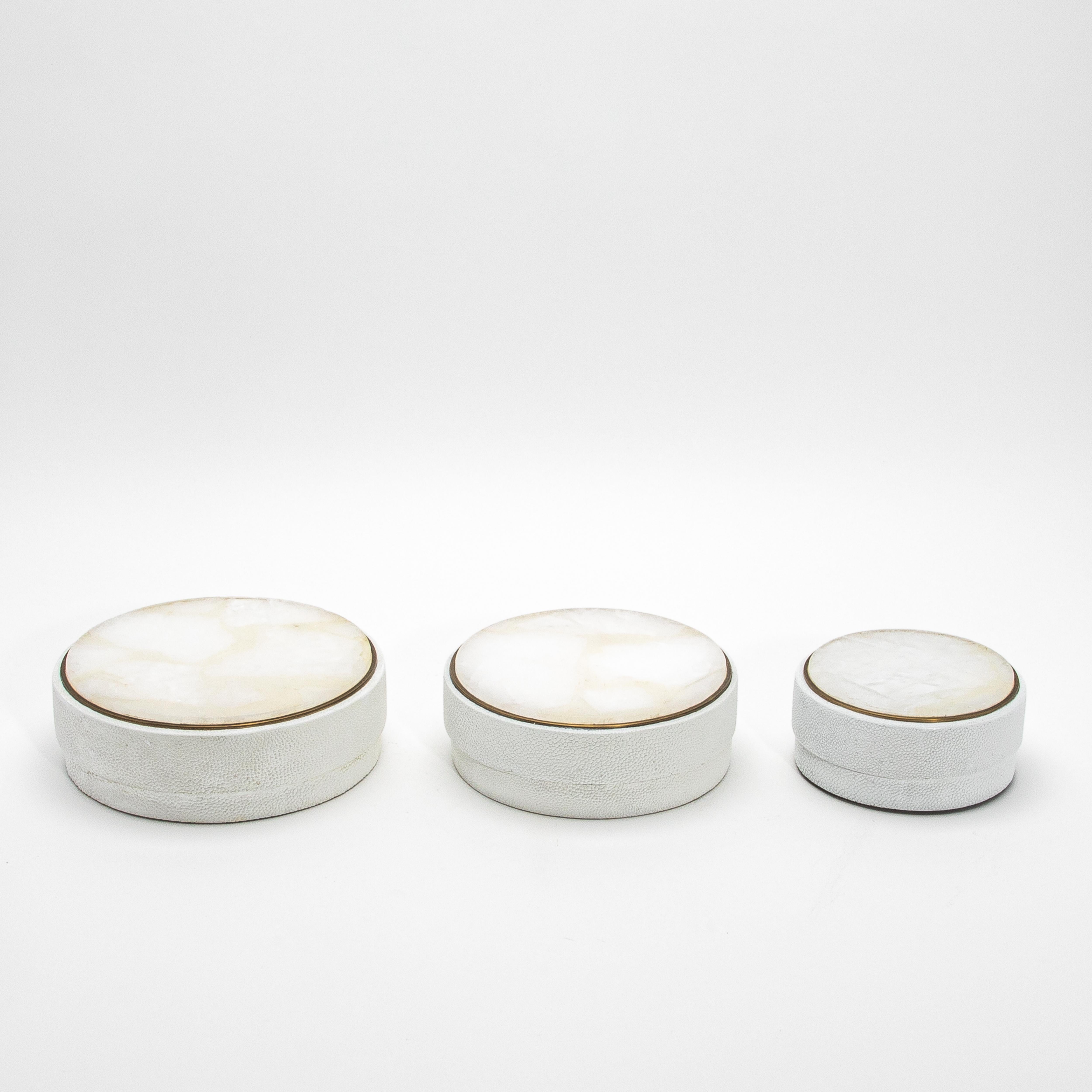 This set of three round boxes by R&Y Augousti is a stunning example of modern artistry blended with timeless luxury. The lids are adorned with rich white quartz, each piece showcasing unique veining that captures light beautifully, framed by a