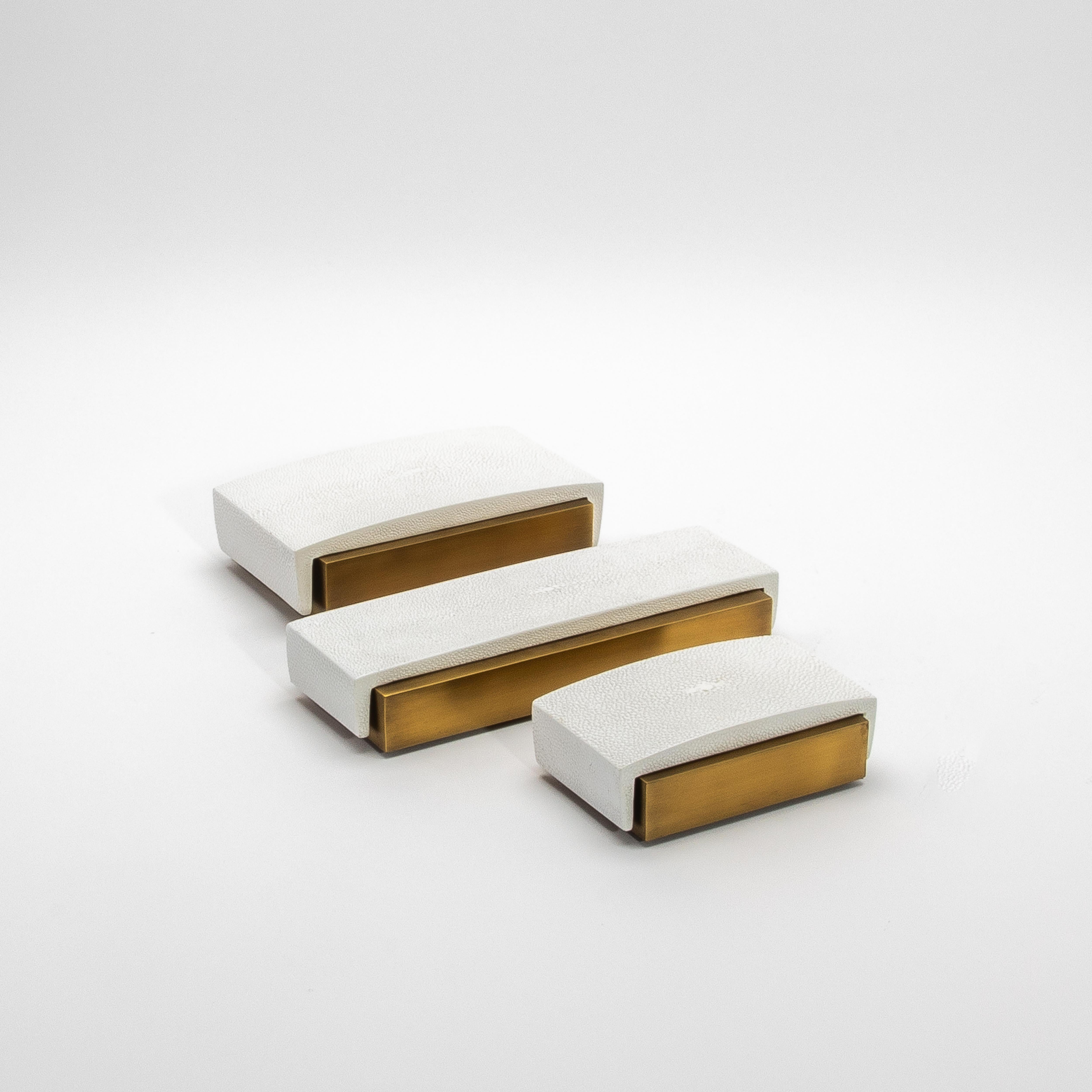 Este elegante conjunto de 3 cajas de escritorio de R&Y Augousti ejemplifica el equilibrio perfecto entre la elegancia moderna y el lujo atemporal. Fabricada en piel de zapa blanca con la parte superior curvada, cada caja queda realzada por su base