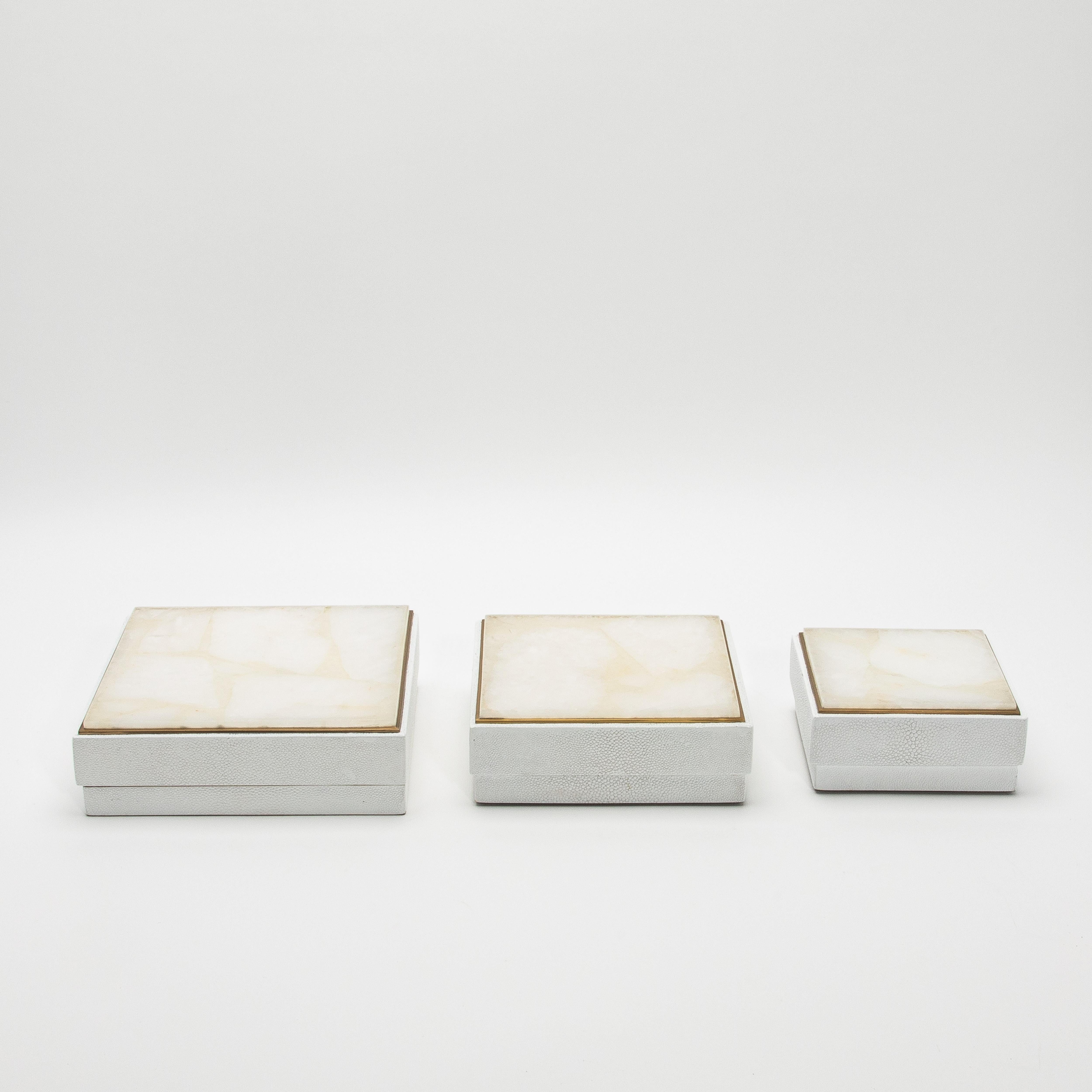 Este conjunto de tres cajas cuadradas de R&Y Augousti es un asombroso ejemplo de diseño refinado, en el que la interacción de materiales crea un cautivador contraste visual. La piel de zapa blanca texturizada forma el cuerpo de cada caja, y su