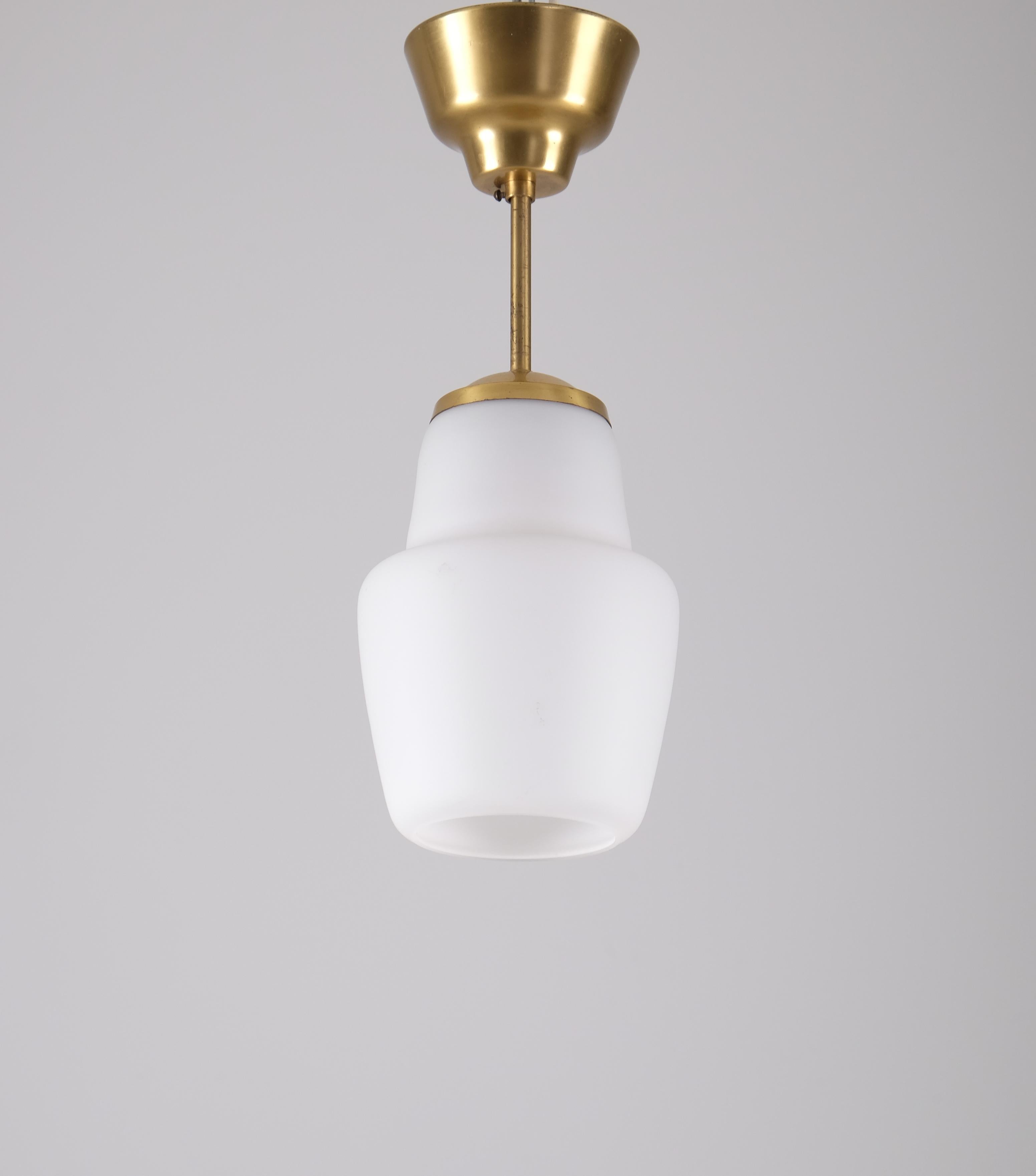 Preciosa lámpara colgante de mediados de siglo, probablemente diseñada por Hans Bergström y fabricada por Ateljé Lyktan en Åhus, Suecia. 
Con una intemporal combinación de latón y cristal opalino, esta lámpara emite un suave y elegante resplandor,