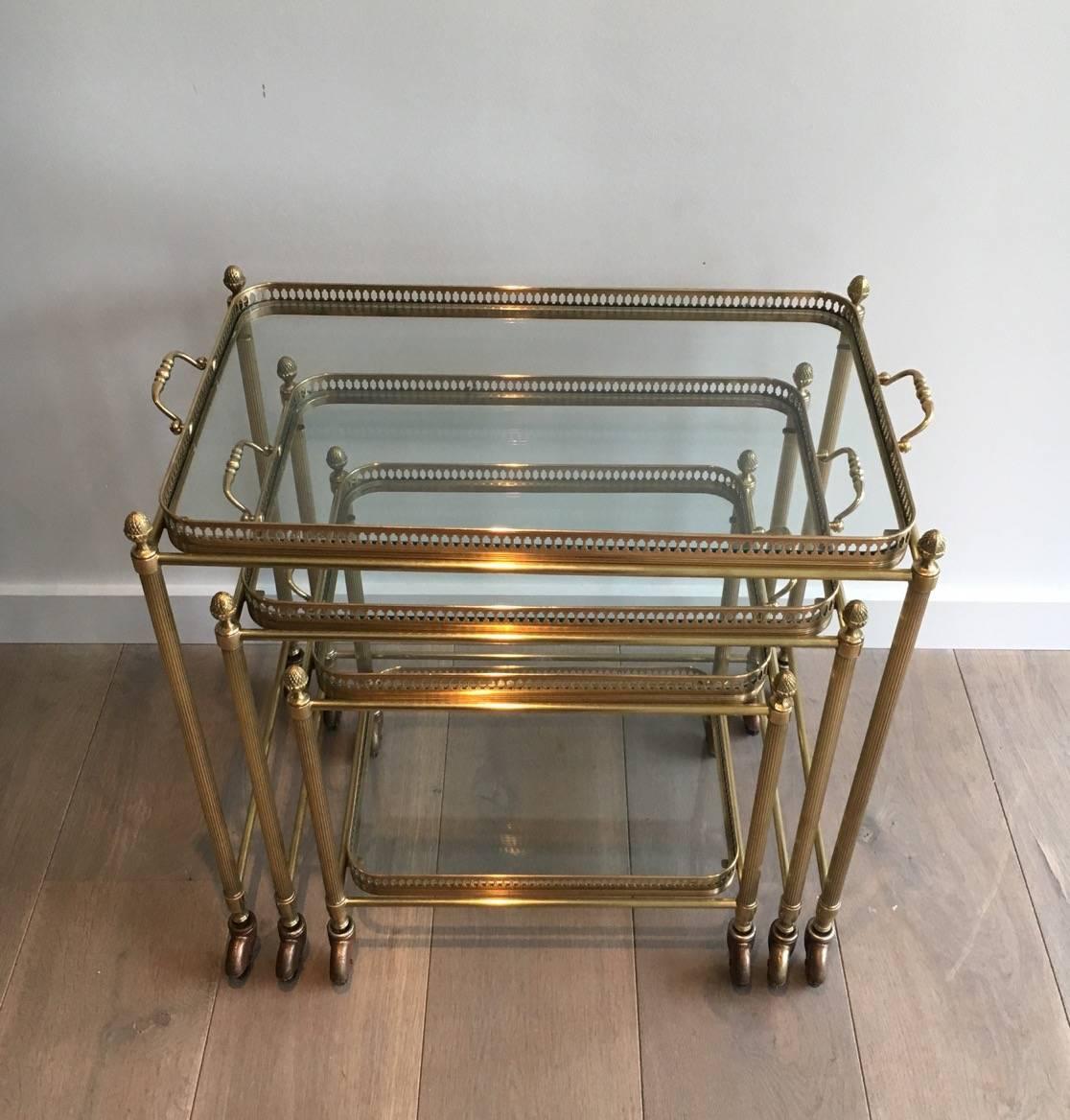 Set of three brass nesting tables on casters with four removable gallery trays. In the style of Maison Baguès. French, circa 1940s.

Here are measurements of each nesting tables:

UPPER: 25.25