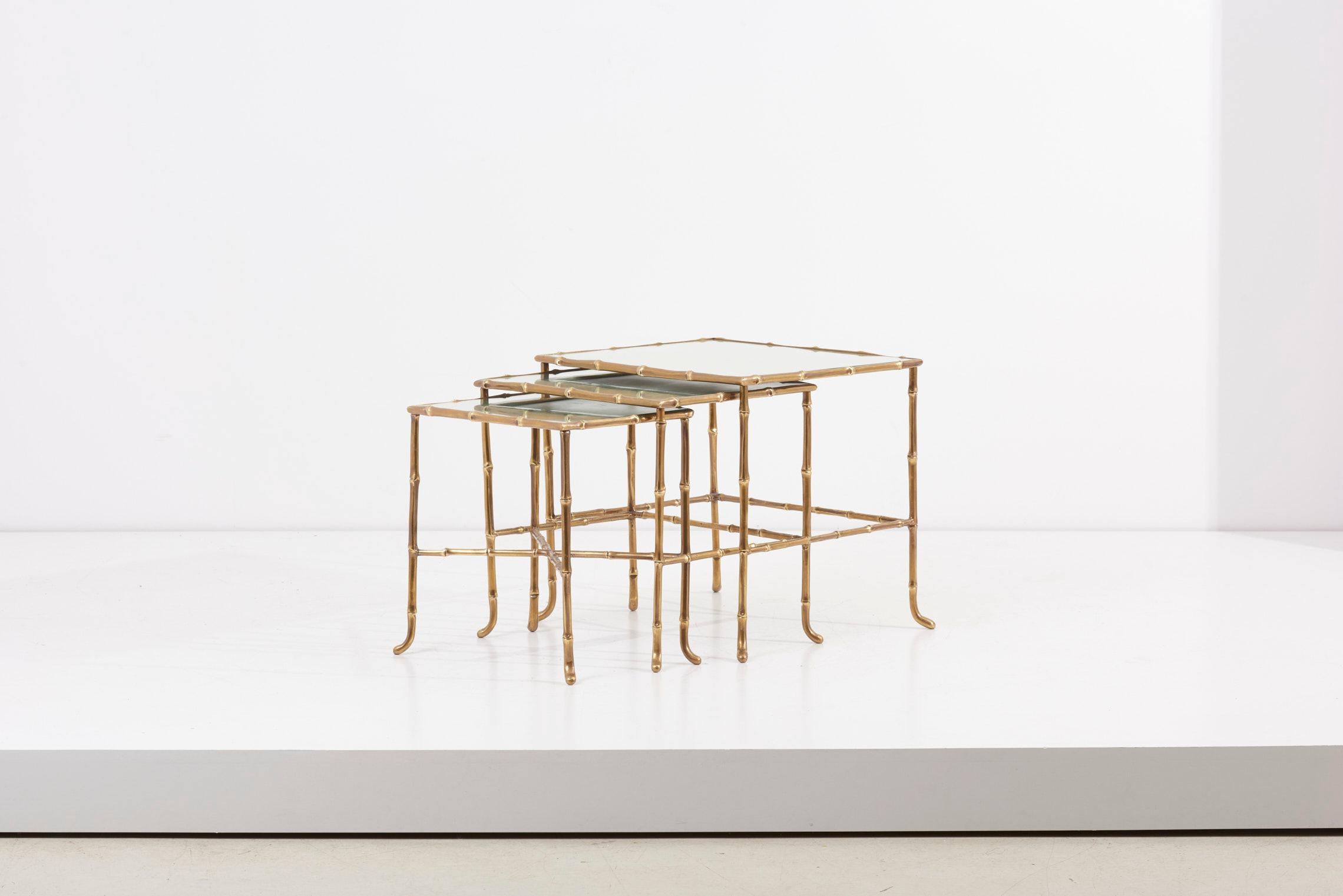Set of three nesting tables in bamboo shape by Maison Baguès in France. Made of brass and with mirror tops. The measurements given apply to the smallest table. 

Measurements table large: D 51.5 cm, W 41.5 cm, H 44.5 cm 
Measurements table