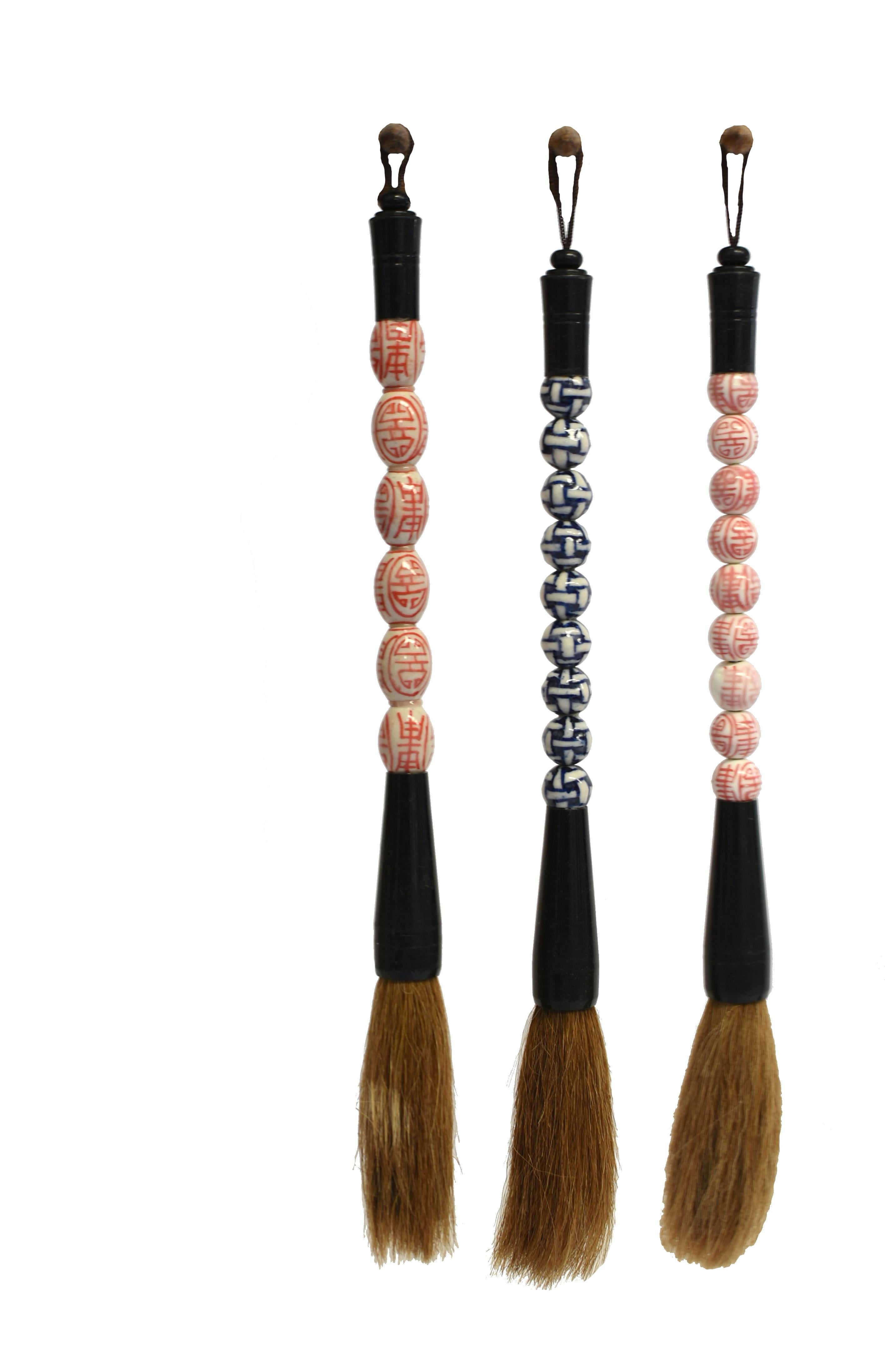 A set of 3 beautiful porcelain handle Chinese calligraphy brushes. The handles with hand painted oval and round porcelain balls of longevity motifs in cinnabar red and basketweave in blue and white. Horse hair. These are excellent brushes for