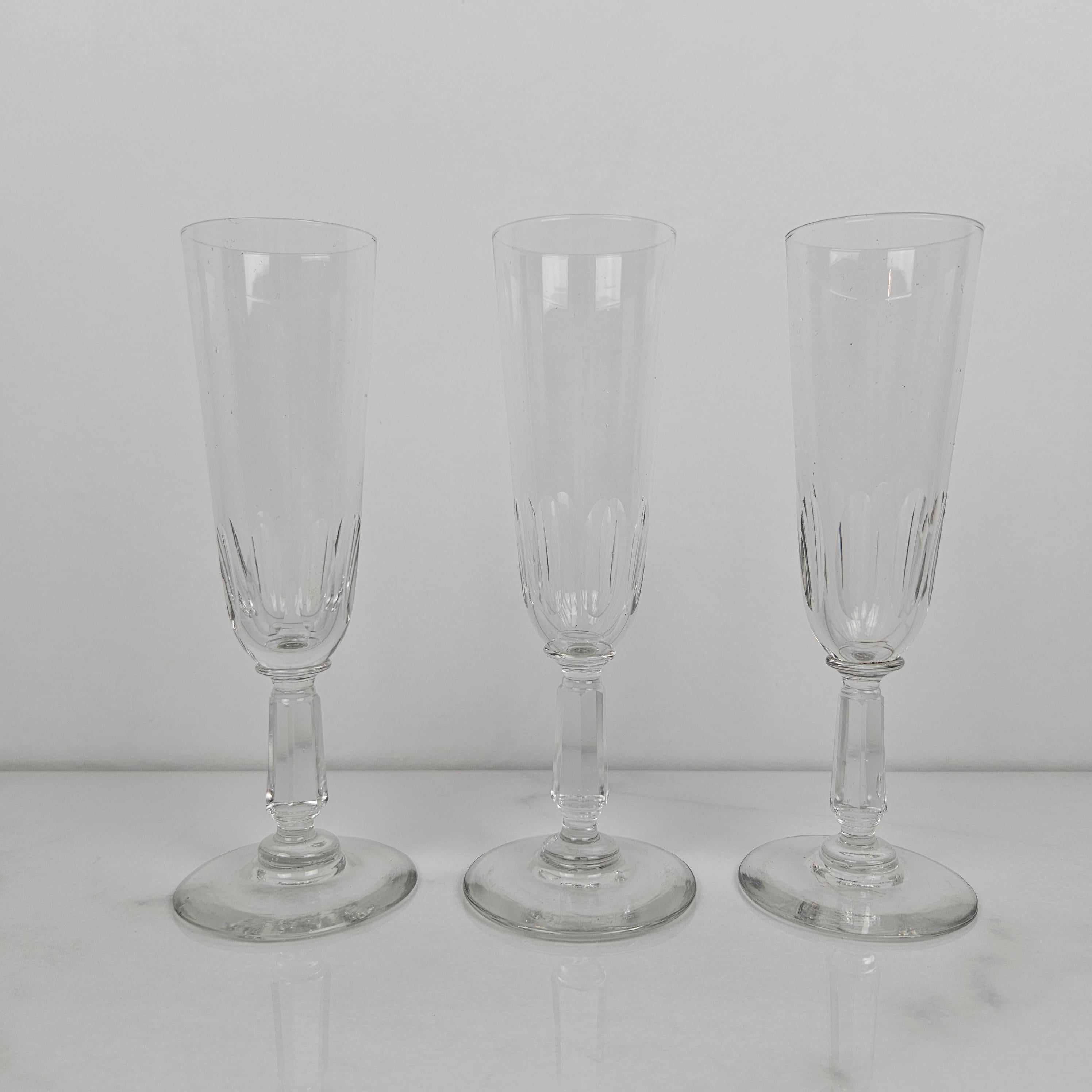 A refined set of 3 antique French champagne glasses, crafted from clear glass circa 1900. 
Each flute features a beautifully cut lower bowl and a stem with decorative detailing, offering both visual interest and a graceful silhouette.
These glasses