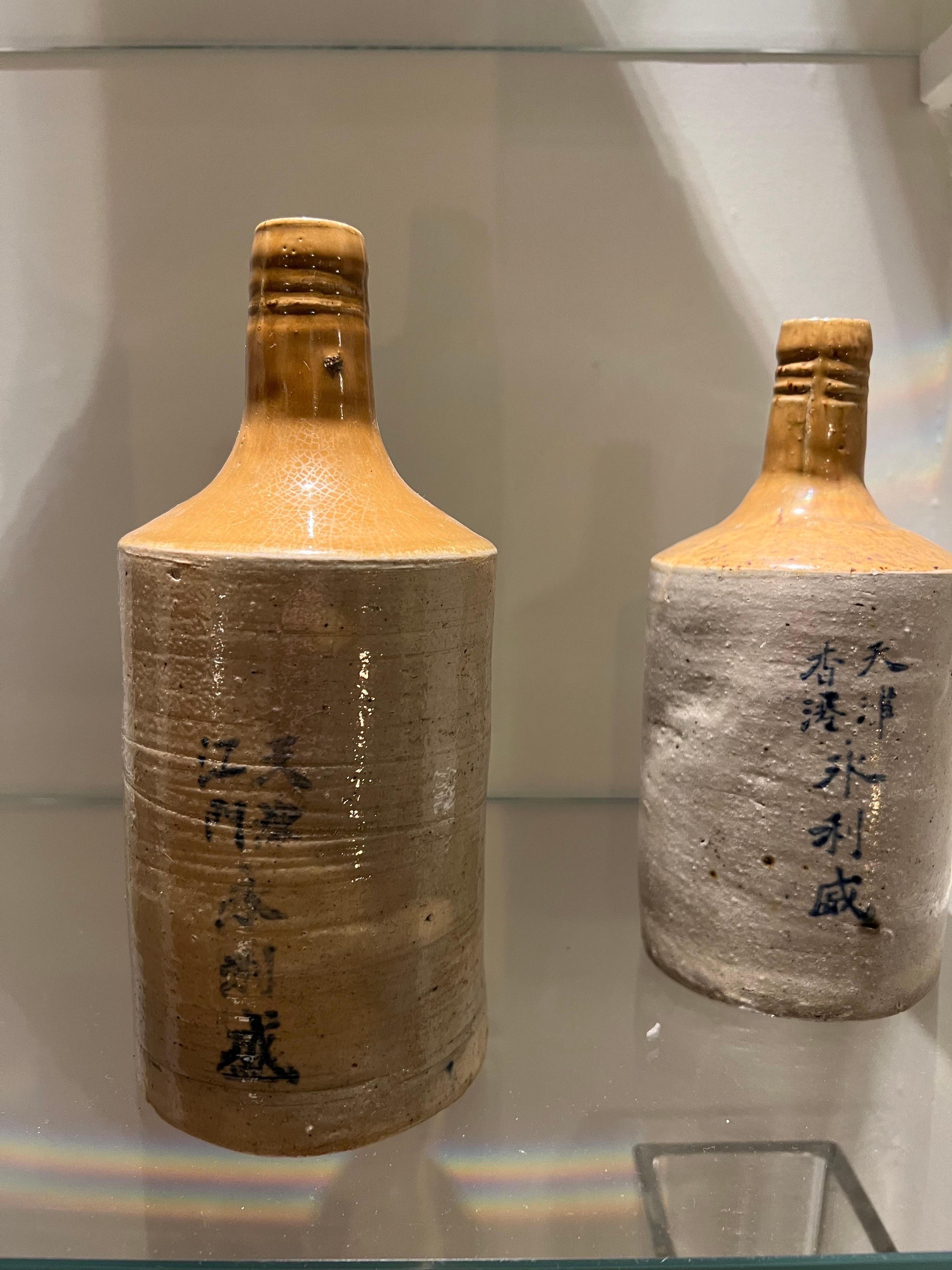 Set of three very decorative rice wine bottles in glazed ceramic. Beige coloured with a brown neck. Blue description on each bottle. 

Dimensions: H 23 cm, D 10 cm.