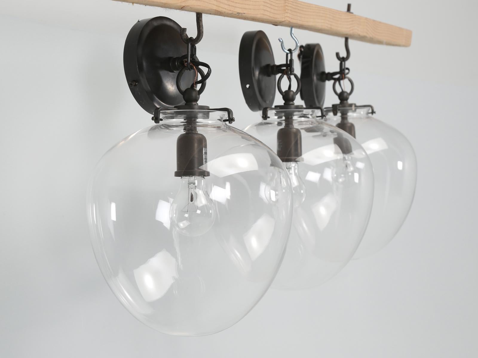 The set of (3) Ceiling Pendant Globe lights were produced by Circa Lighting / Thomas O’Brien Katie Acorn Pendant in dark bronze with clear globes. This set of (3) pendants were purchased and never installed. 
**Height provided includes the chain