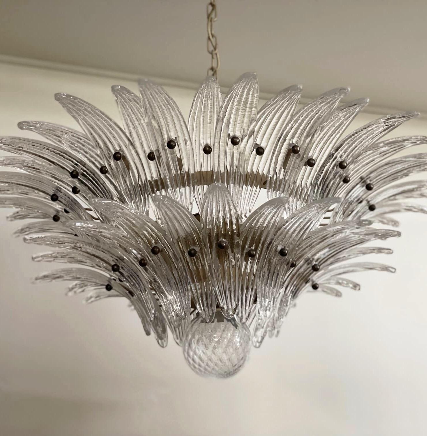 Set of three Bold Eclectic Palma Murano Chandeliers in the style of Flamingo.
Italian Palmette chandelier in 1970s style with clear Murano glass leaves arranged in two tiers and mounted on a metal frame. The lamp structure is painted in a