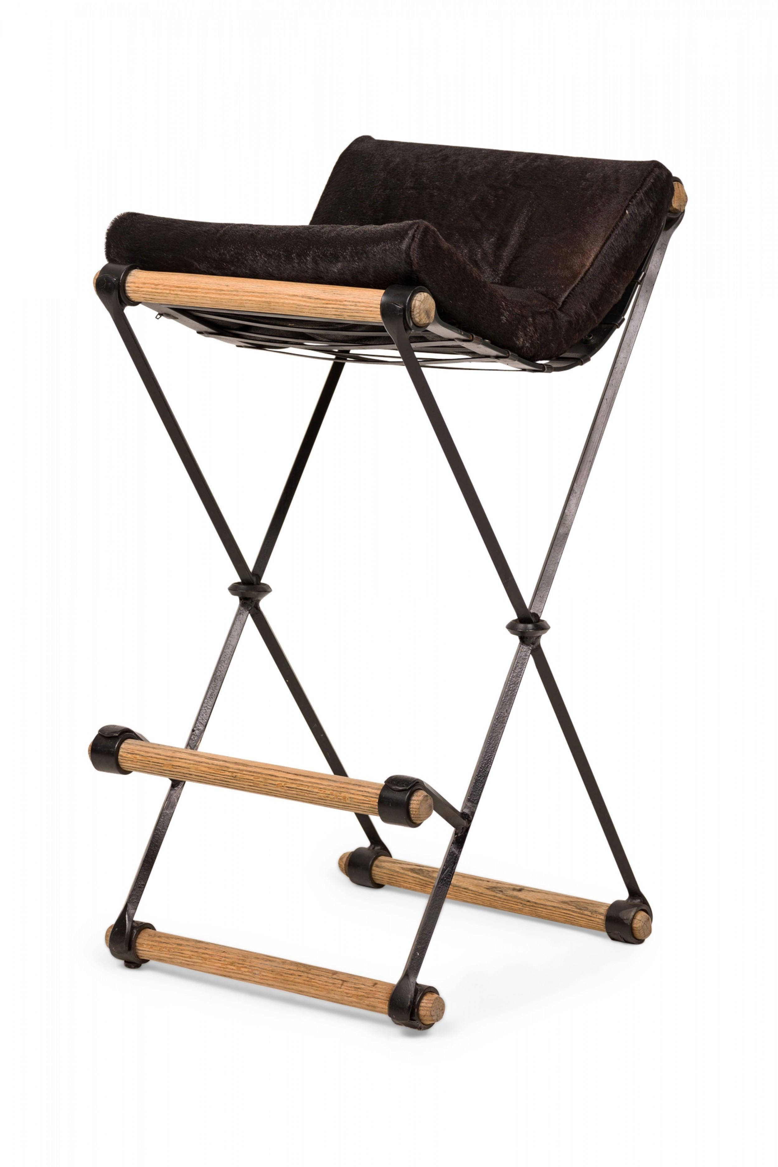 Set of 3 Mid-Century American (1970s) X-frame bar stools with upholstered black faux cowhide seat pads resting on sturdy iron and oak frames. (CLEO BALDON FOR TERRA OF CALIFORNIA)(PRICED AS Set) (Other examples in different upholstery: DUF0830,