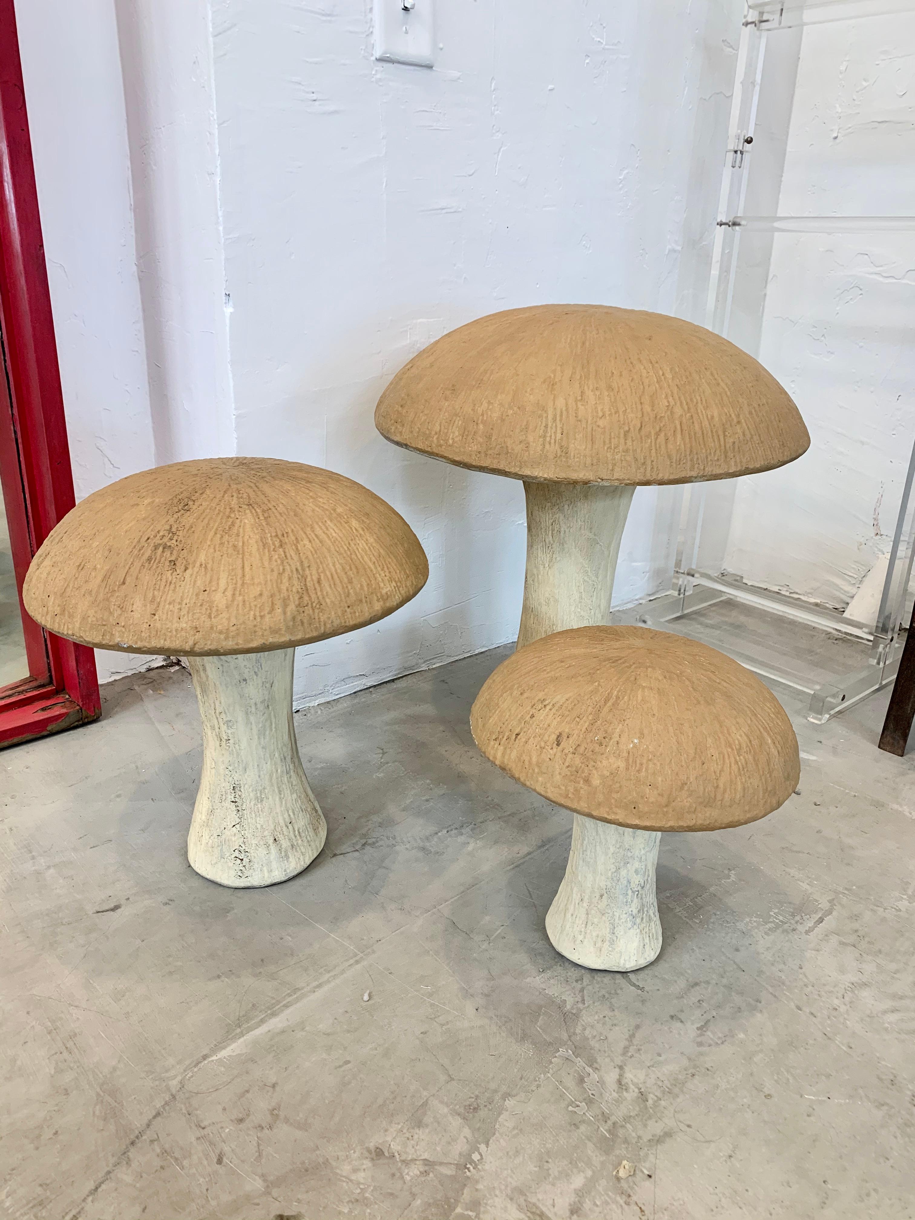 Set of 3 concrete mushroom sculptures from the 1970s. Large, medium and small. Light colored stalk with brown top. Can be used as a stool in the garden or placed inside or out as sculpture. Good vintage condition and coloring.

Sold as a set of 3