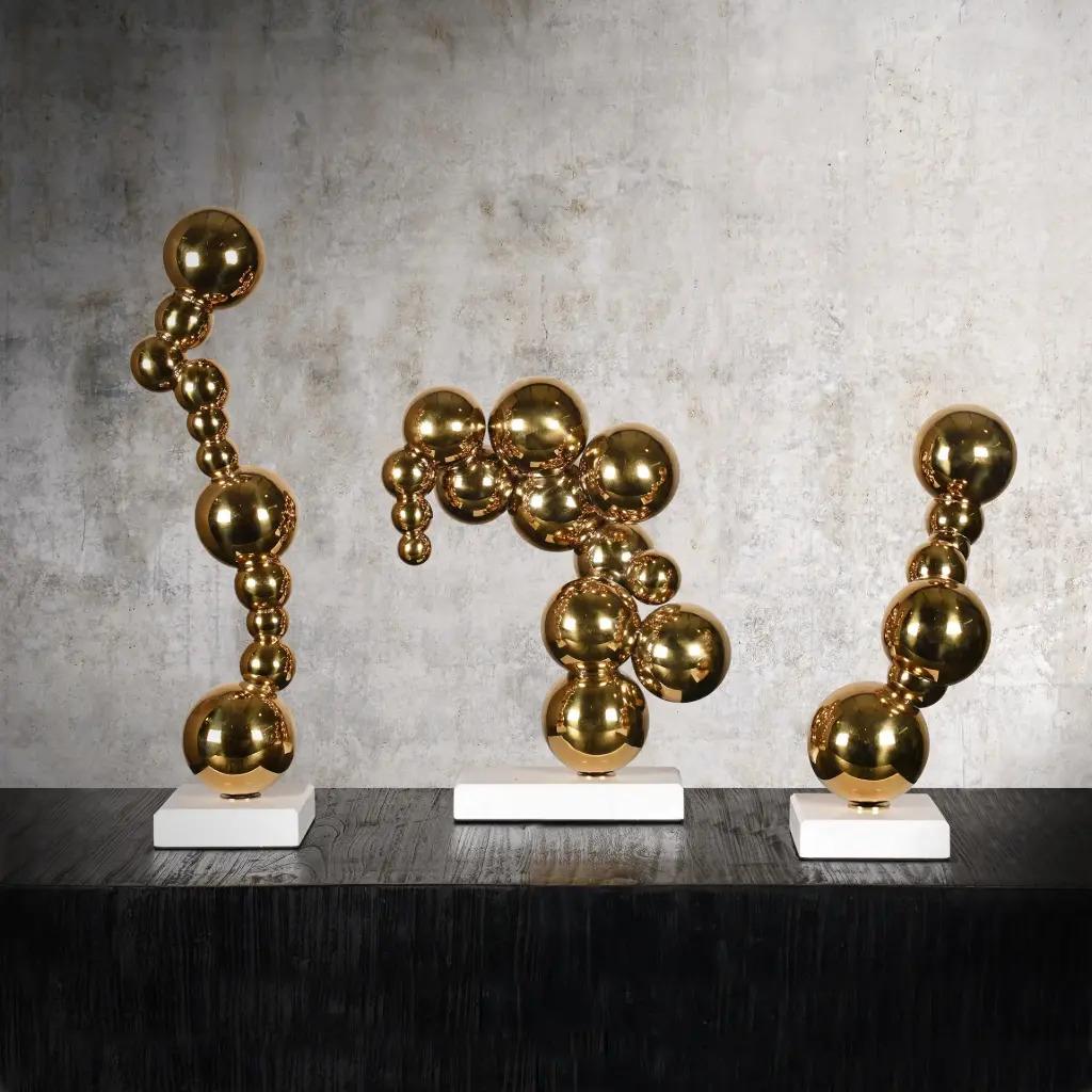 This elegant set of 3 contemporary bubble sculptures combines golden bronze spheres with refined white marble bases. Their organic and fluid composition recalls the monumental works displayed at the Guggenheim Museum in Bilbao.
Each sculpture seems