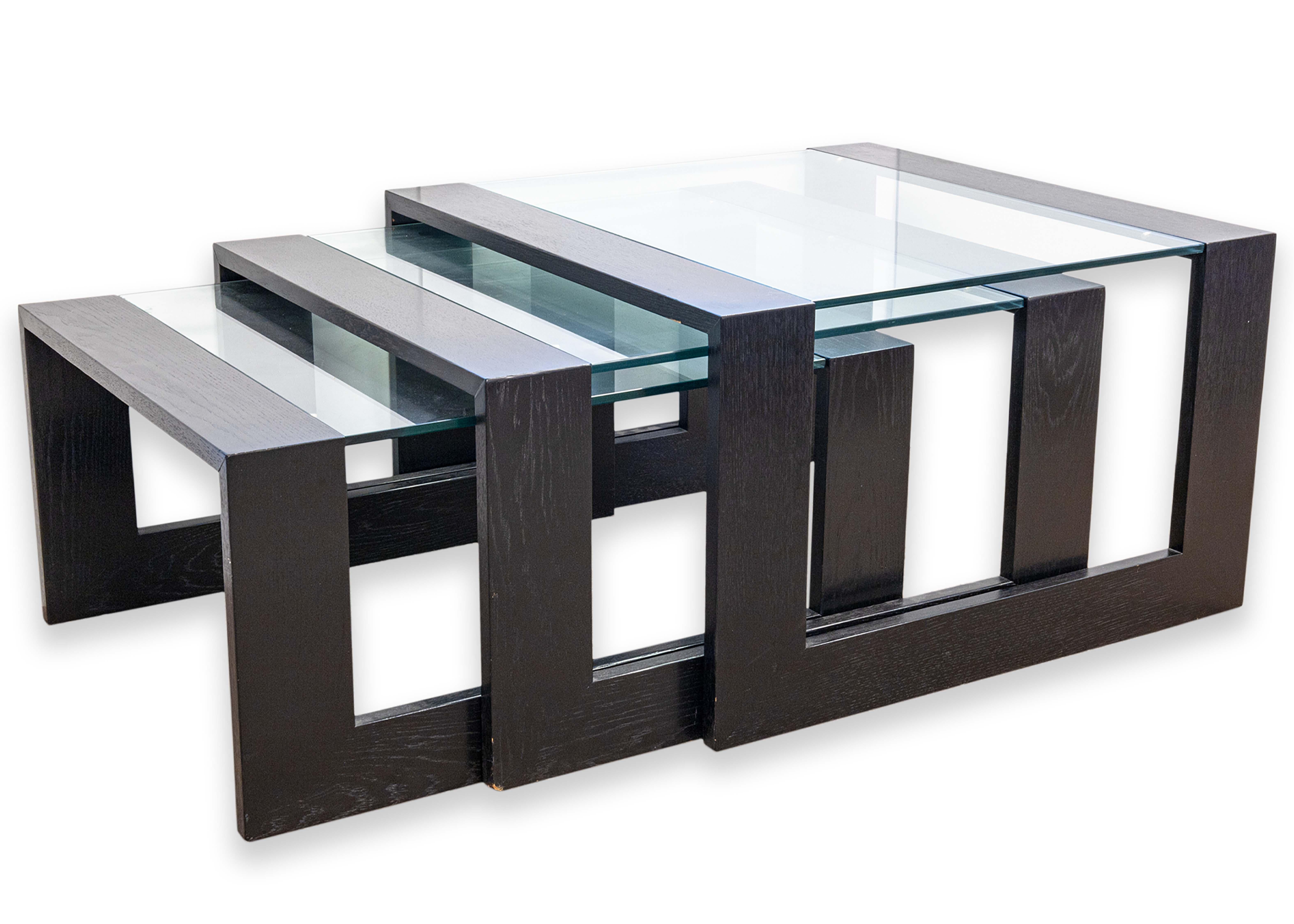 Un ensemble de 3 tables gigognes modernes et contemporaines. Cet ensemble de tables gigognes présente un design épuré en bois et en verre. Le cadre est en bois noir et les plateaux de table sont en verre teinté. Chacune de ces tables est