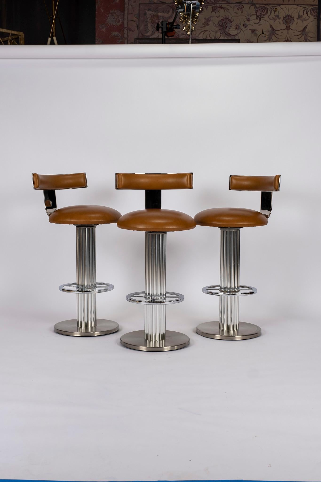 A set of three Design For Leisure chrome barstools newly upholstered in an Italian cognac leather.