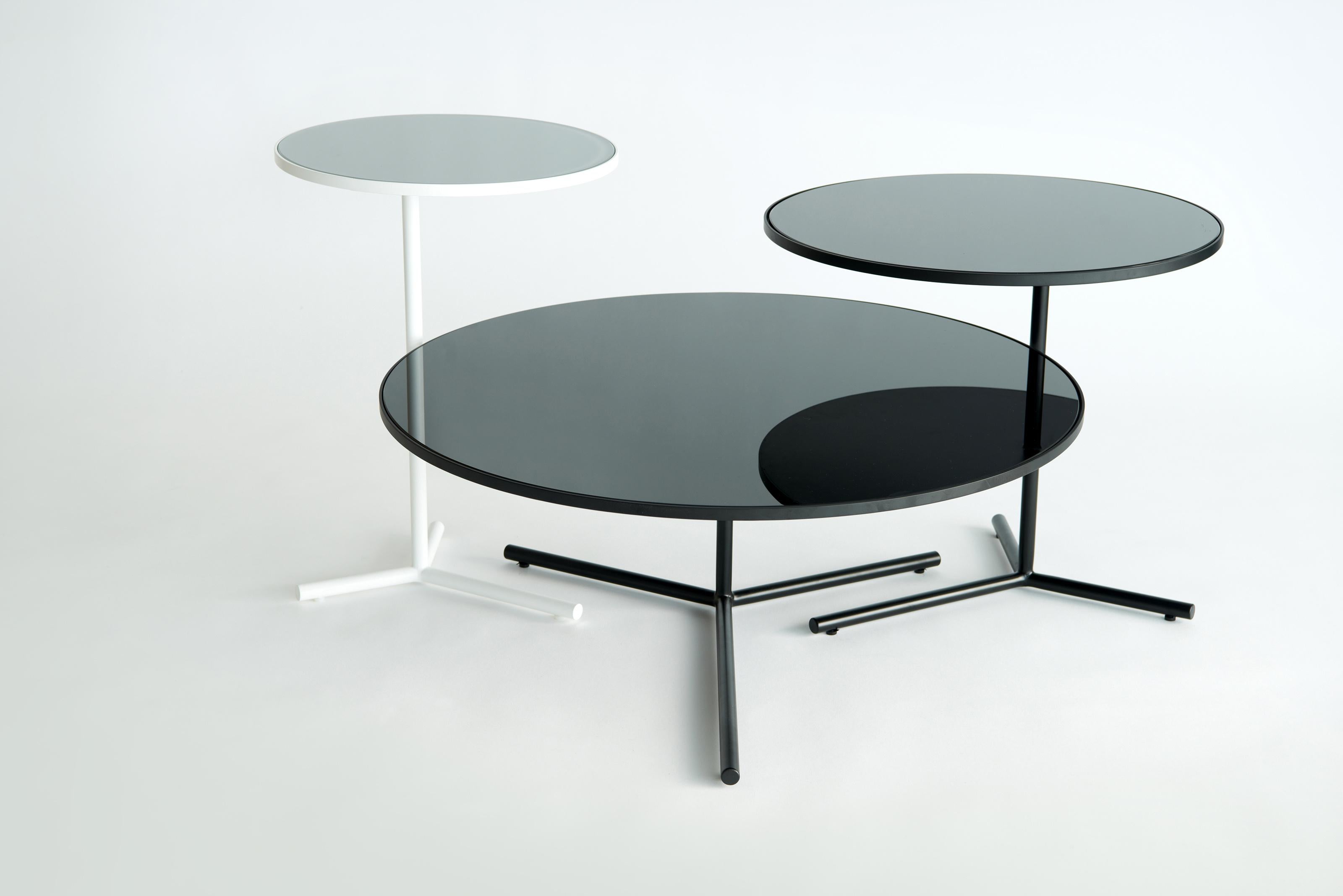 Set Of 3 Downtown Tables by Phase Design
Dimensions: Large: Ø 76,2 x H 30,5 cm. 
Medium: Ø 50,8 x H 45,7 cm. 
Small: Ø 38,1 x H 53,34 cm.
Materials: Spandrel glass and powder-coated steel.

Solid steel base available in flat or gloss black and white