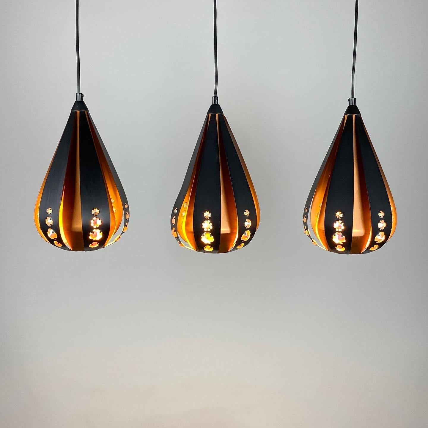 Ensemble de trois magnifiques lampes suspendues en forme de goutte d'eau par Werner Schou pour Coronell Electrical Denmark, produites entre 1960 et 1970. 

Fabriqué à partir de cuivre, de lattes de métal noir et de pièces de verre rectangulaires