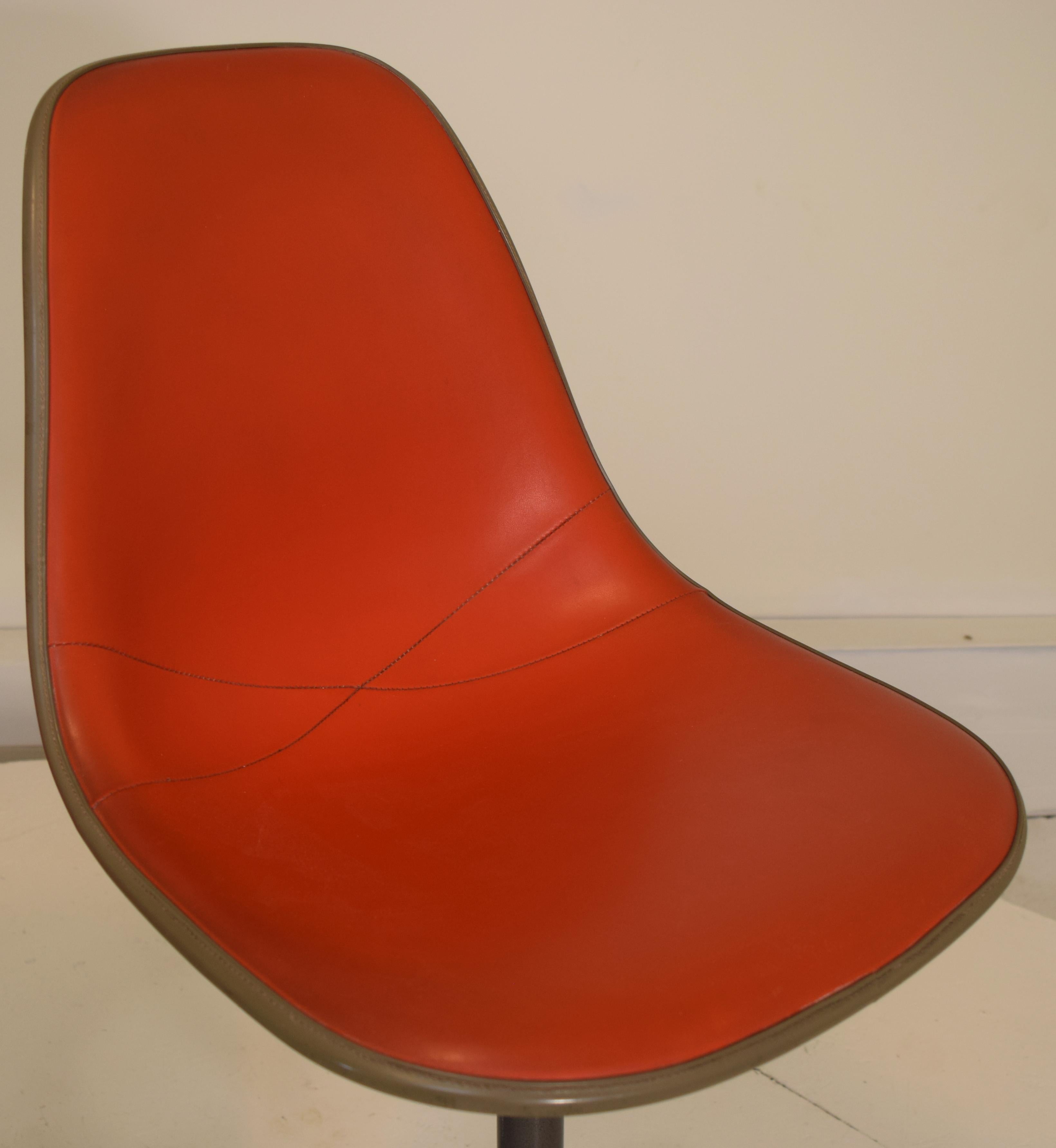 Set of 3 swivel stools by Ray and Charles Eames and Herman Miller in orange vinyl. All identical from original consignor and purchased together in 1972. The task chairs have a gunmetal finish to the lower sections with aluminum bases on castors.