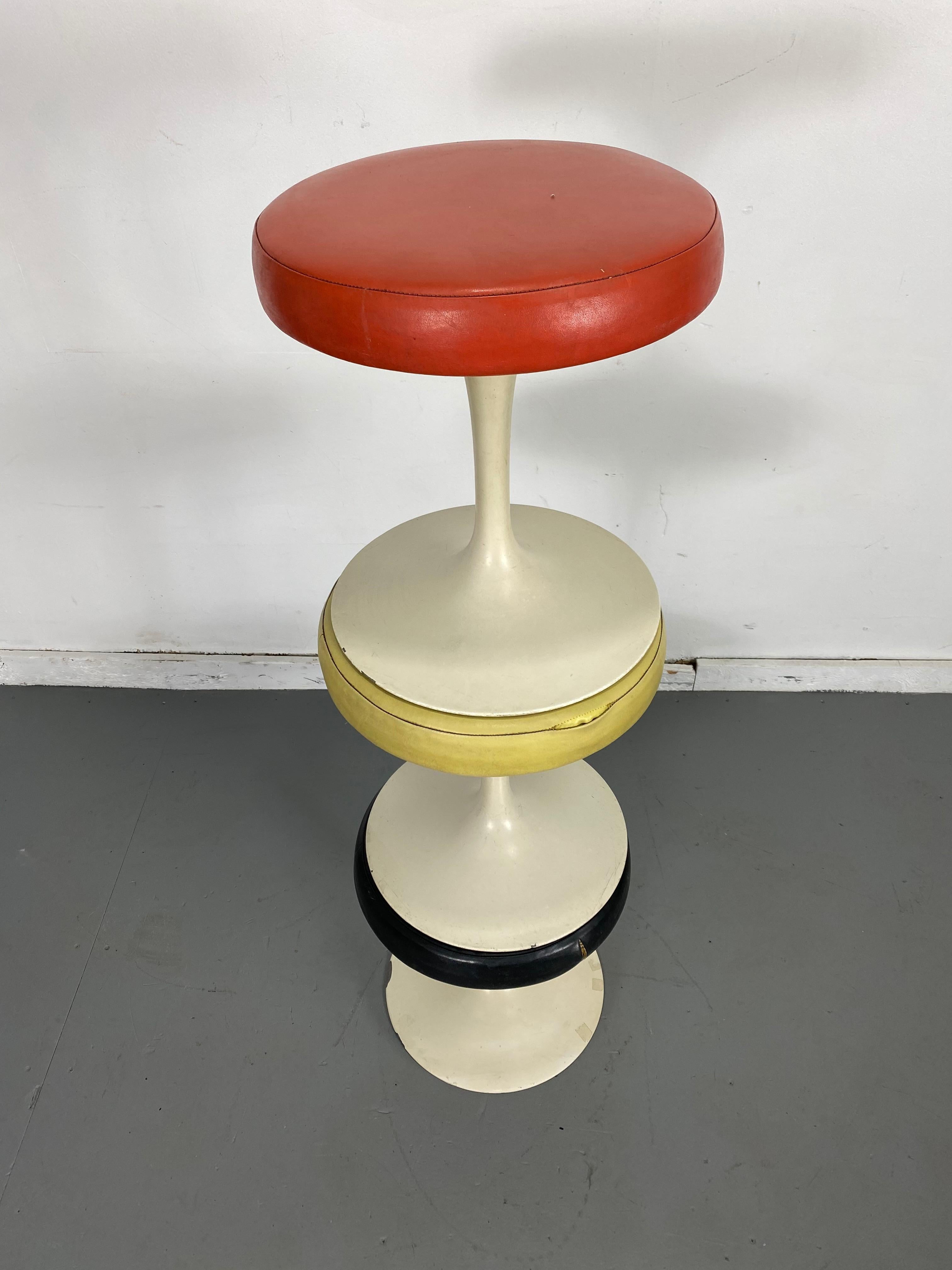 Set of 3 Early Knoll Associates Tulip Saarinen stools.... designed by Eero Saarinen for Knoll Associates, Madison Avenue, NYC. Early bow tie label. Retain Original upholstery., minor paint loss and tear to black stool, minor leather separation to