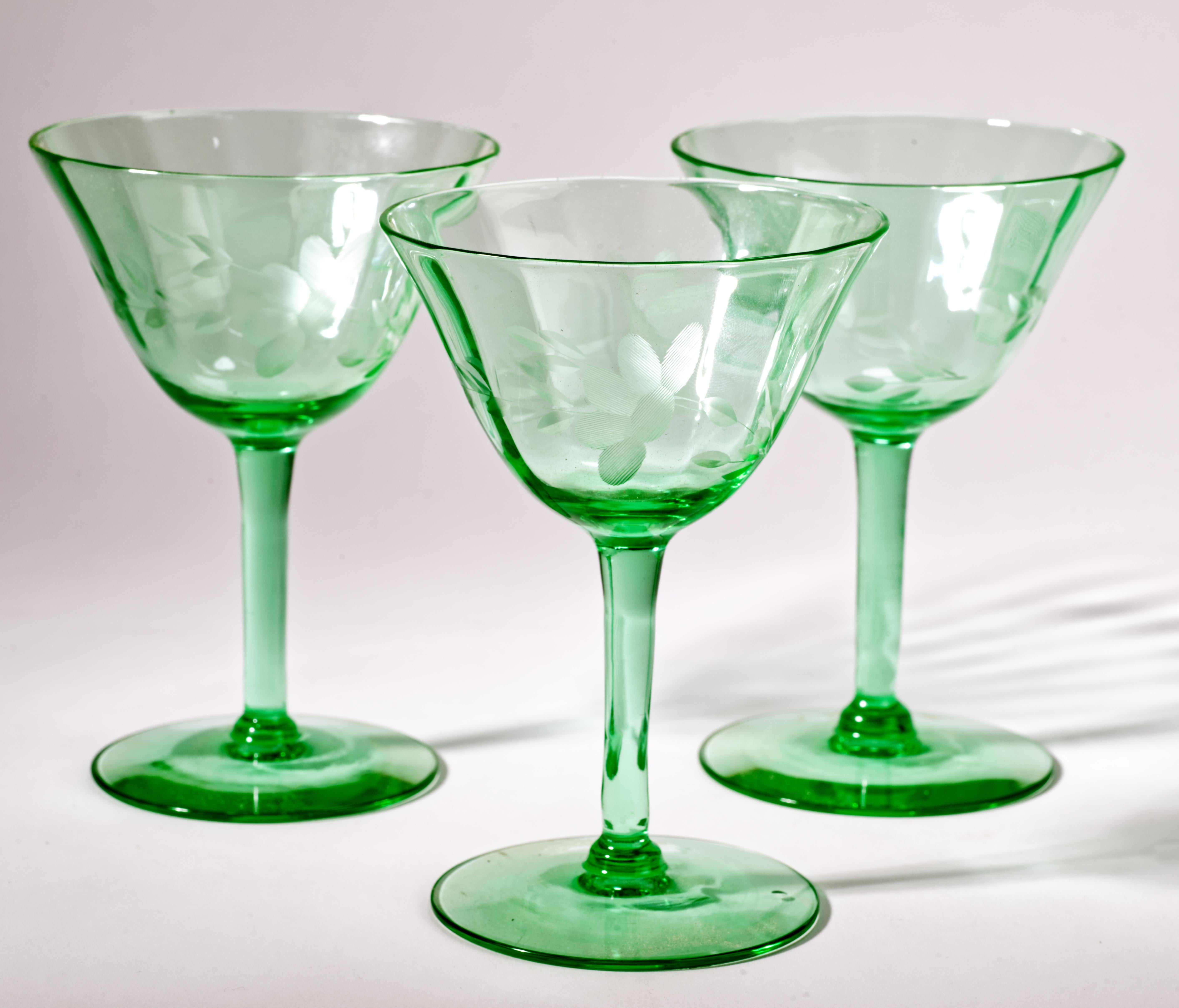 I bicchieri da cocktail vintage Mid-Century Modern sono stati realizzati in vetro verde uranio con una texture op-art che prosegue dagli steli ai bordi delle coppe. I bicchieri sono decorati con fiori astratti incisi e si illuminano intensamente