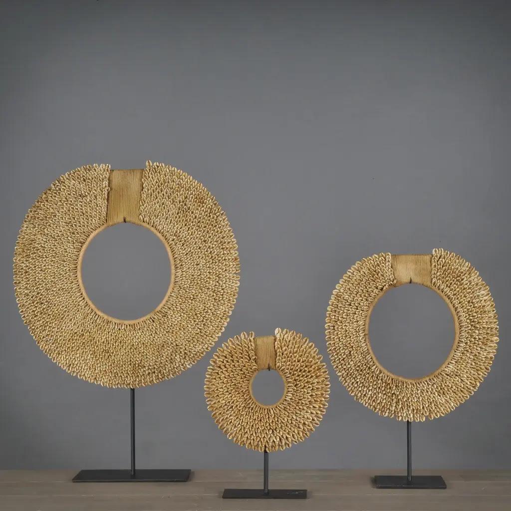 Ce lot de trois colliers ethniques en coquillages dorés est issu de l'art tribal traditionnel d'Indonésie. Chaque collier est fabriqué à la main à partir de coquillages naturels, soigneusement disposés et montés sur un support en acier noir mat.