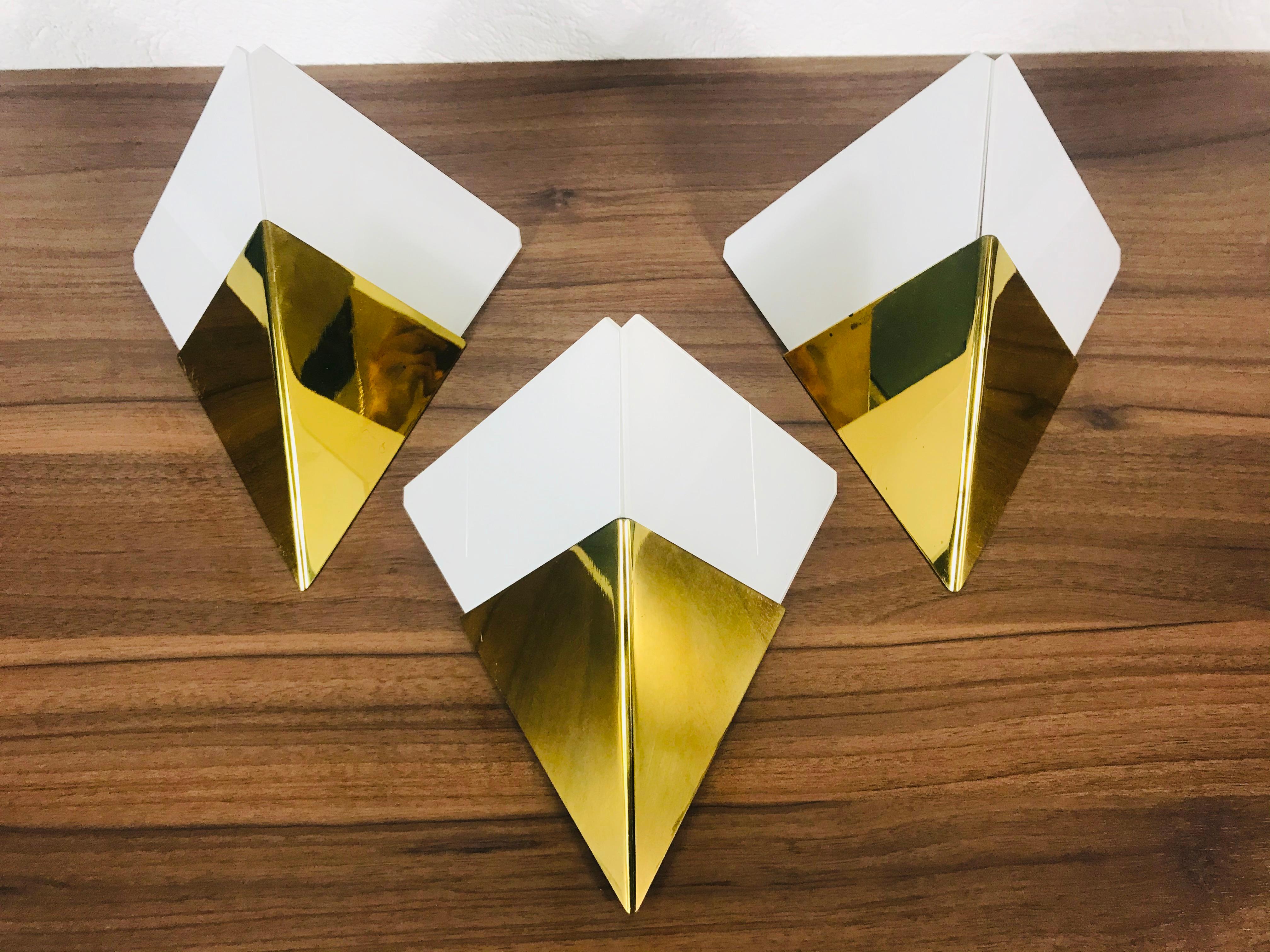 Amazing set of wall lamps by the Austrian brand Kalmar Franken made in the 1960s. Triangle white ice glasses which are stuck to the brass body.

The light requires one E14 light bulb.
