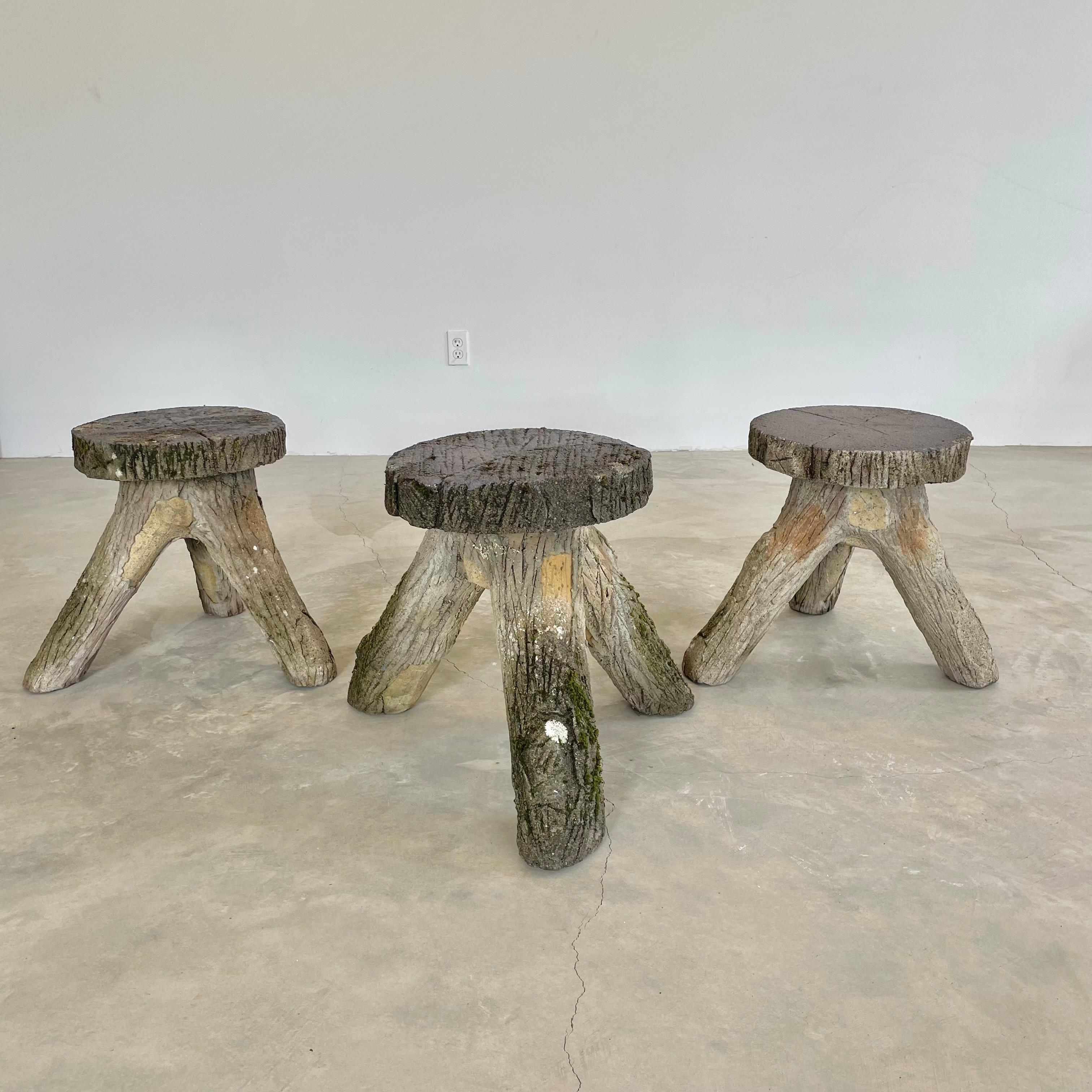 Stunning concrete faux-bois tripod stools, circa 1970s. Detailed design including realistic bark to knots and wood grain can be seen throughout each stool. Years of patina and weathering gives each piece in the set a stunningly unique look. As these