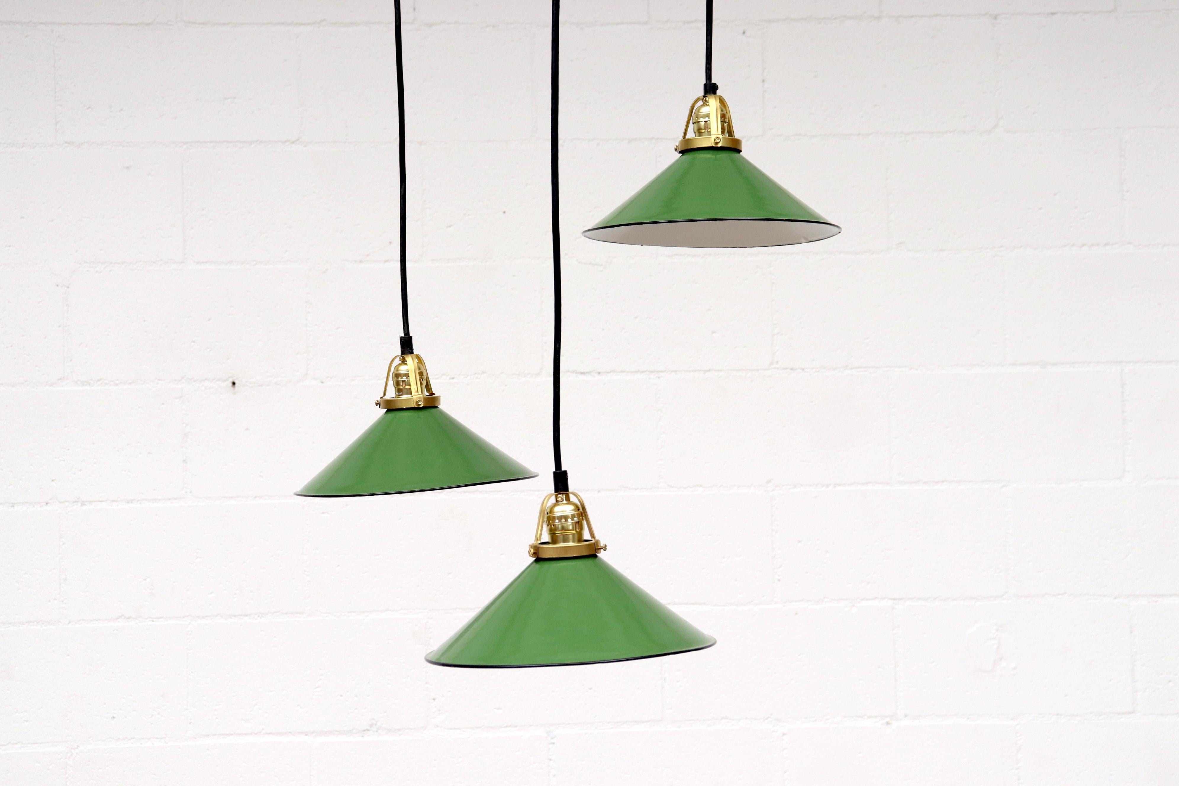 French industrial Minimalist pendant lights. Green enameled metal discs with new brass hardware. Shades in original condition with some enamel wear and moderate visible scratching. Wear is consistent with their age. Shapes and sizes may vary